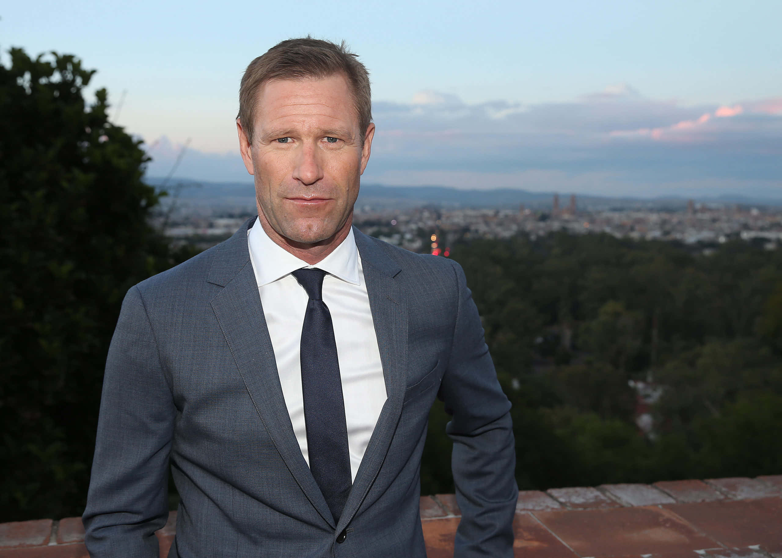 Aaron Eckhart met Blou Lug Stad Muurpapier