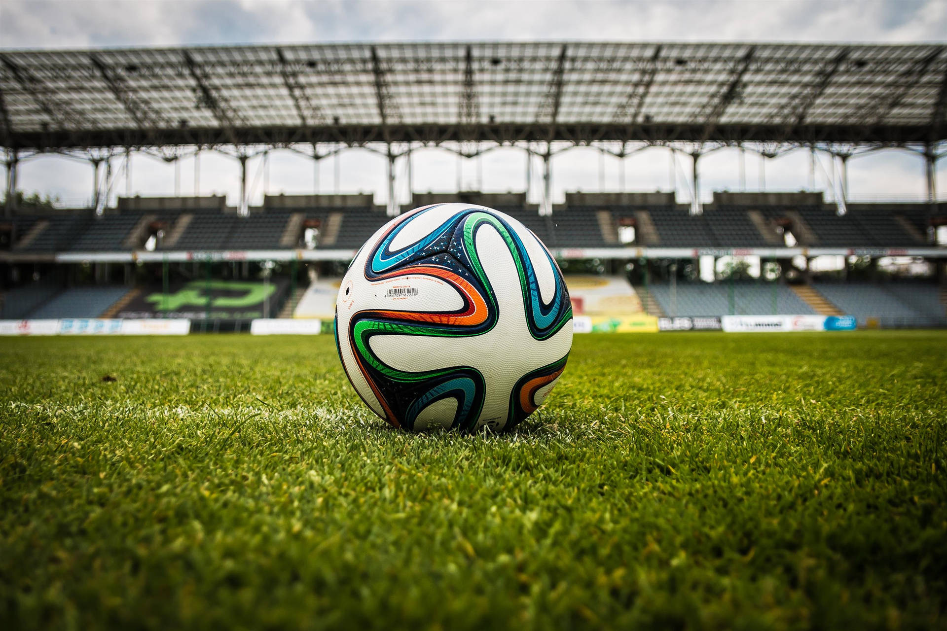 Sokkerstadion sokkerbal groen gras lessenaar agtergrond.