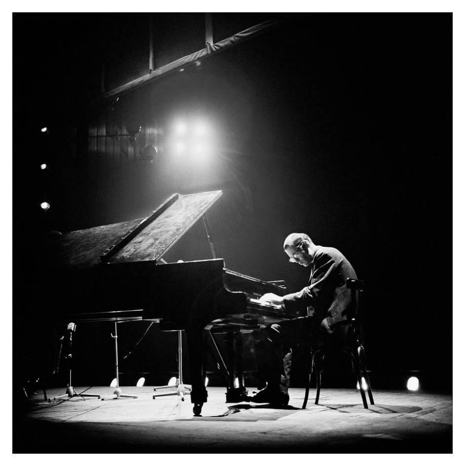 Bill Evans op verhoog met kollig terwyl hy klavier speel Muurpapier
