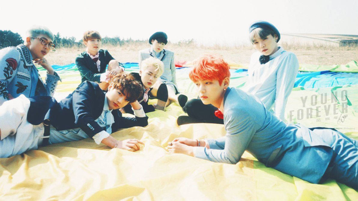 BTS-lede wat op 'n kombers op die strandgrond lê gedurende die somer.