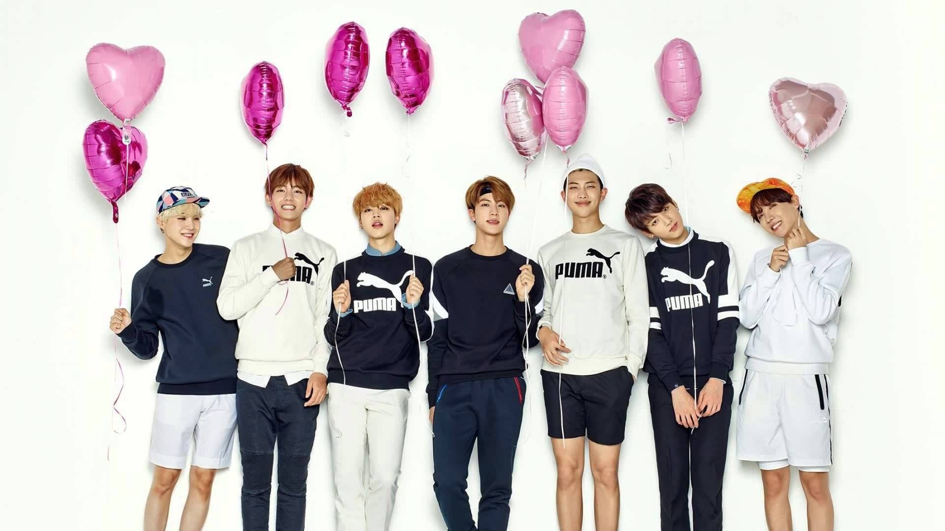 BTS wat glimlag en 'n hartballon vashou agtergrond.
