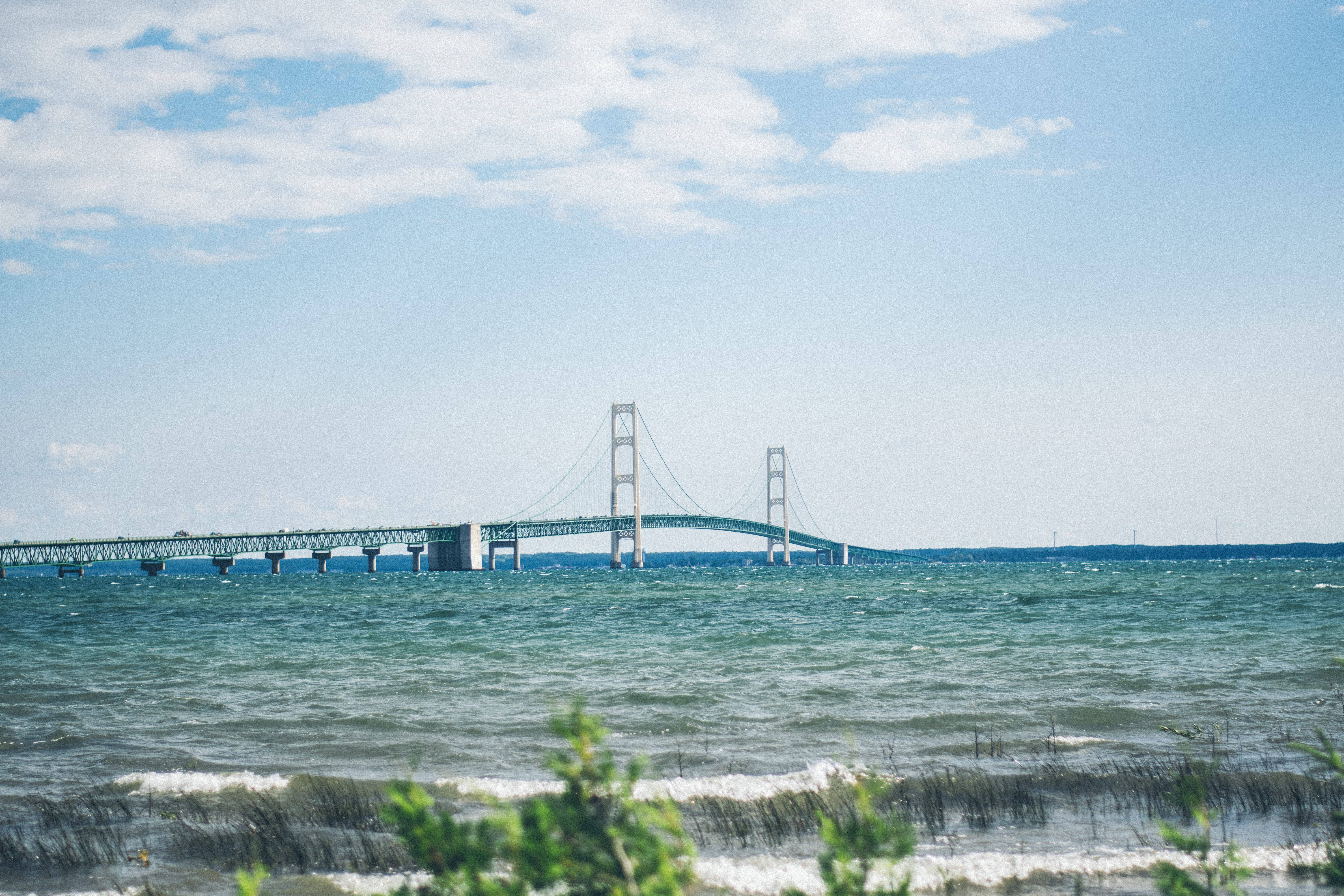 Die Majestueuse Mackinac-brug wat oor die Rustige Blou Waters Strek Muurpapier