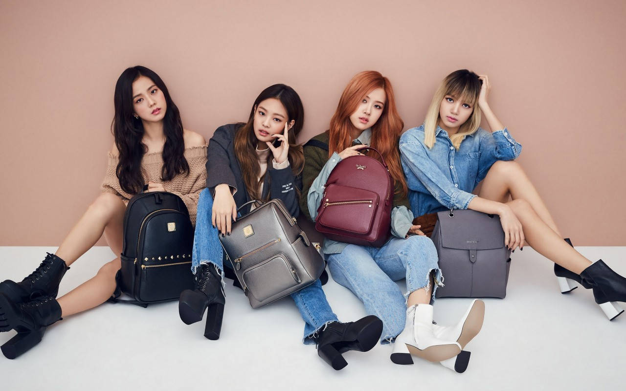 Blackpink-lede met rugsakke op beige muur-agtergrond