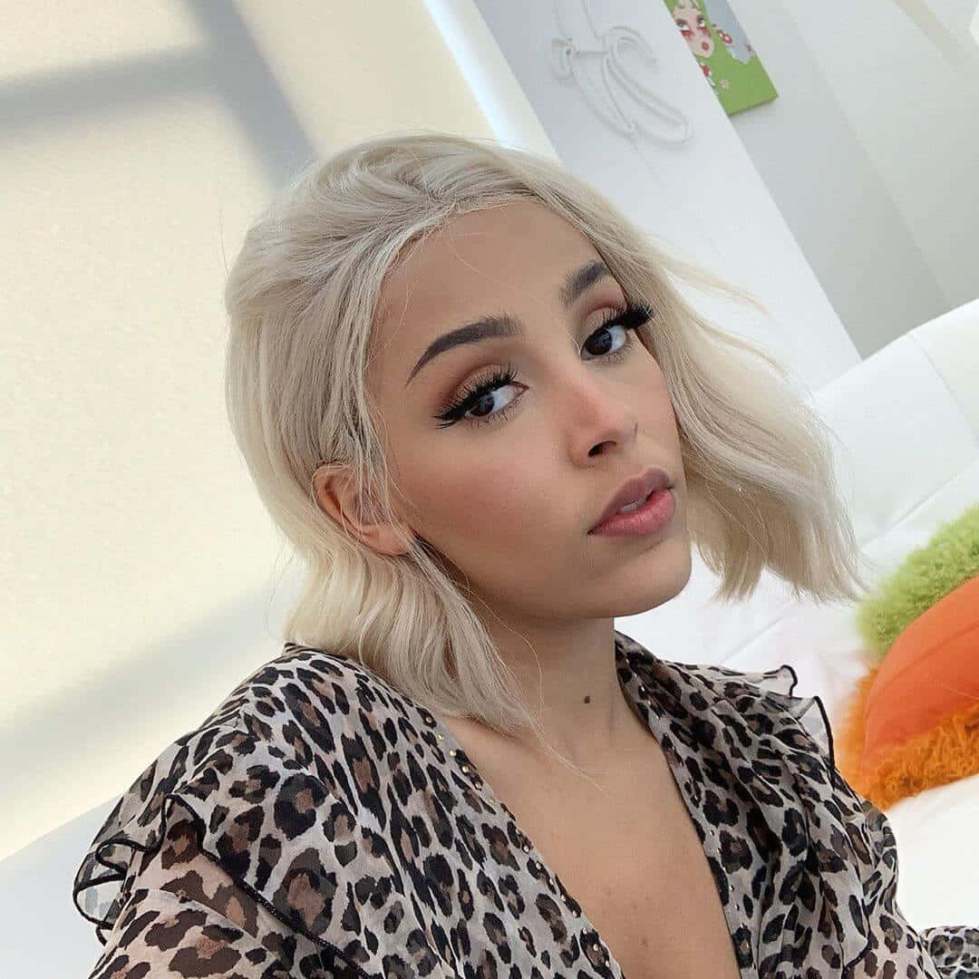 Doja Cat wat haar skoonheid wys met glinster-oogskadu en 'n helder glimlag. Muurpapier