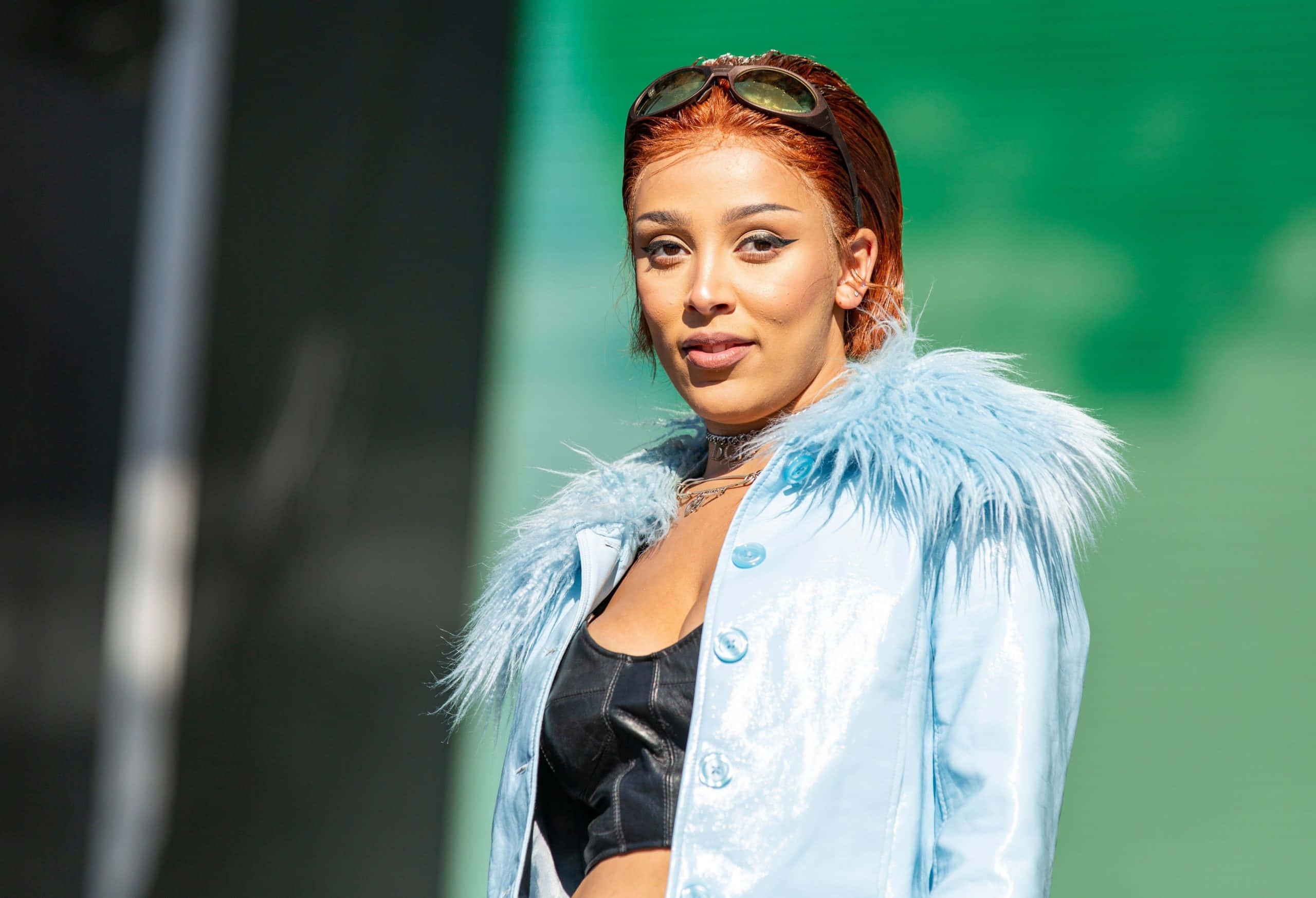 Doja Cat wat poseer in 'n uitrusting van leer en latex Muurpapier