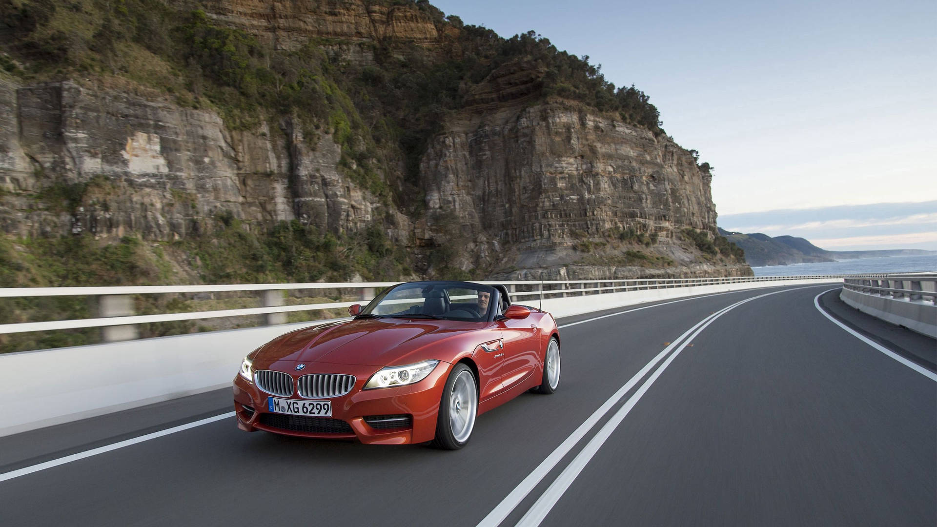 Oranje BMW Z4 motor op pad langs berg agtergrond