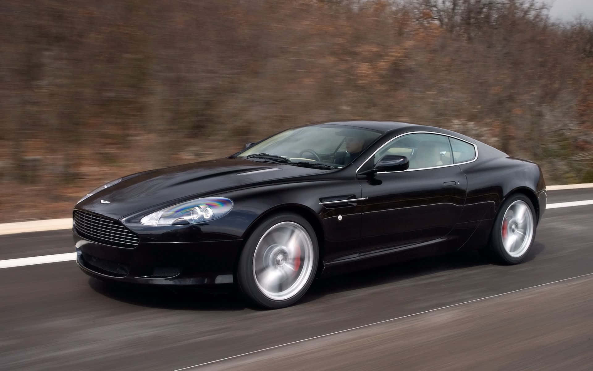 Elegante Aston Martin DB9 op 'n oop pad Muurpapier