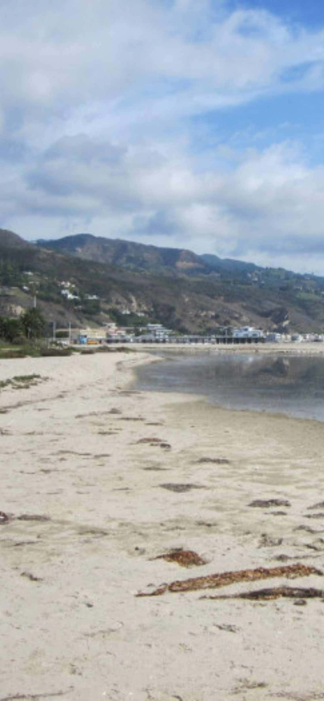 Geniet skilderagtige uitsigte oor Malibu van jou iPhone XS af Muurpapier