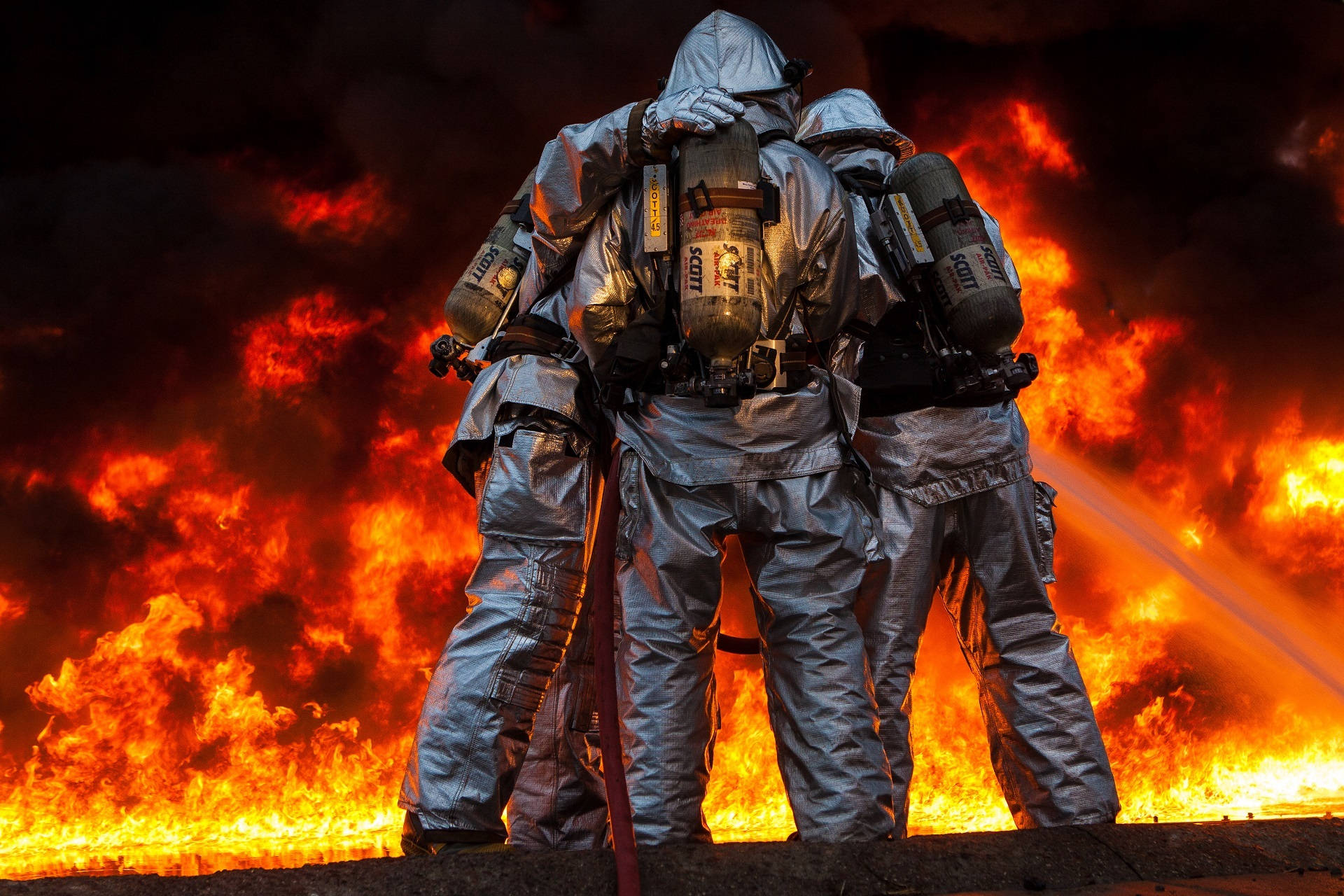 Groep Brandweermanne wat op 'n Brand Reageer Muurpapier