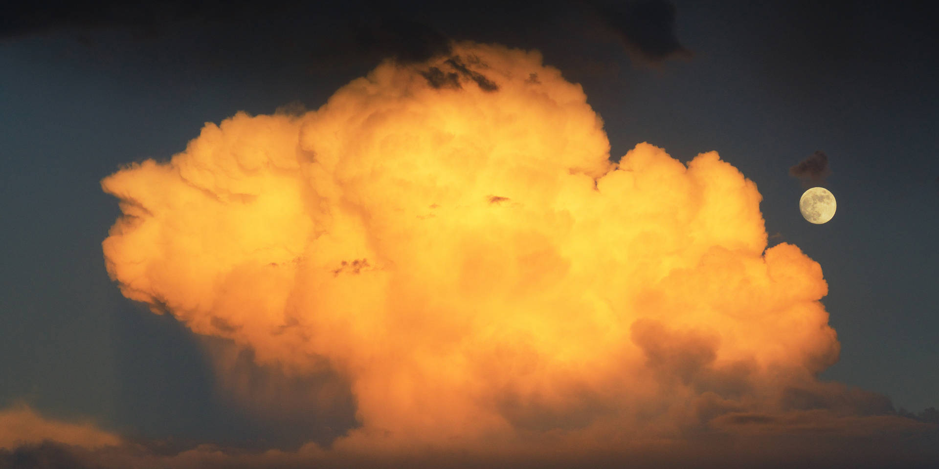 Maan en wolke wat die sonlig van sonsondergang weerkaats. Volmaan wat wys voordat die son ondergaan.