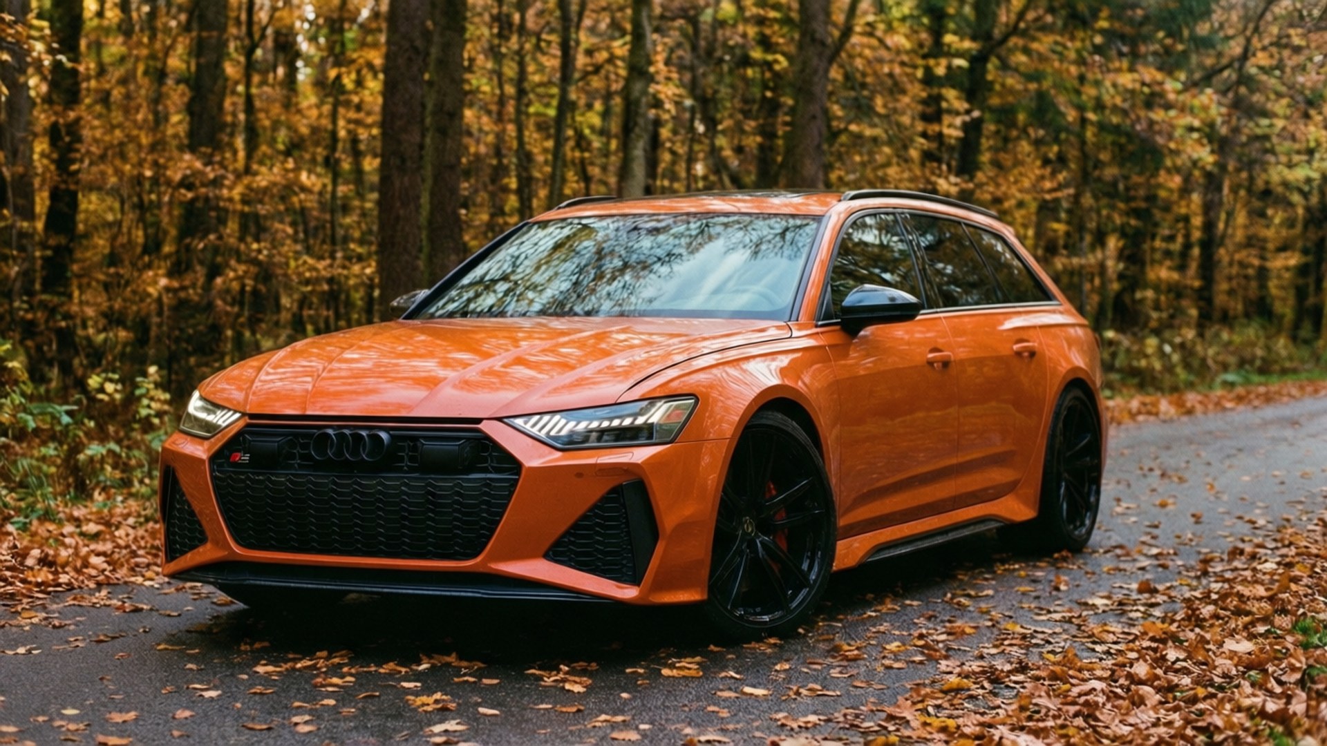 ’n Oranje Audi RS6 Avant op ’n herfsbosveldpad met vallende blare. — Koel motors Muurpapier