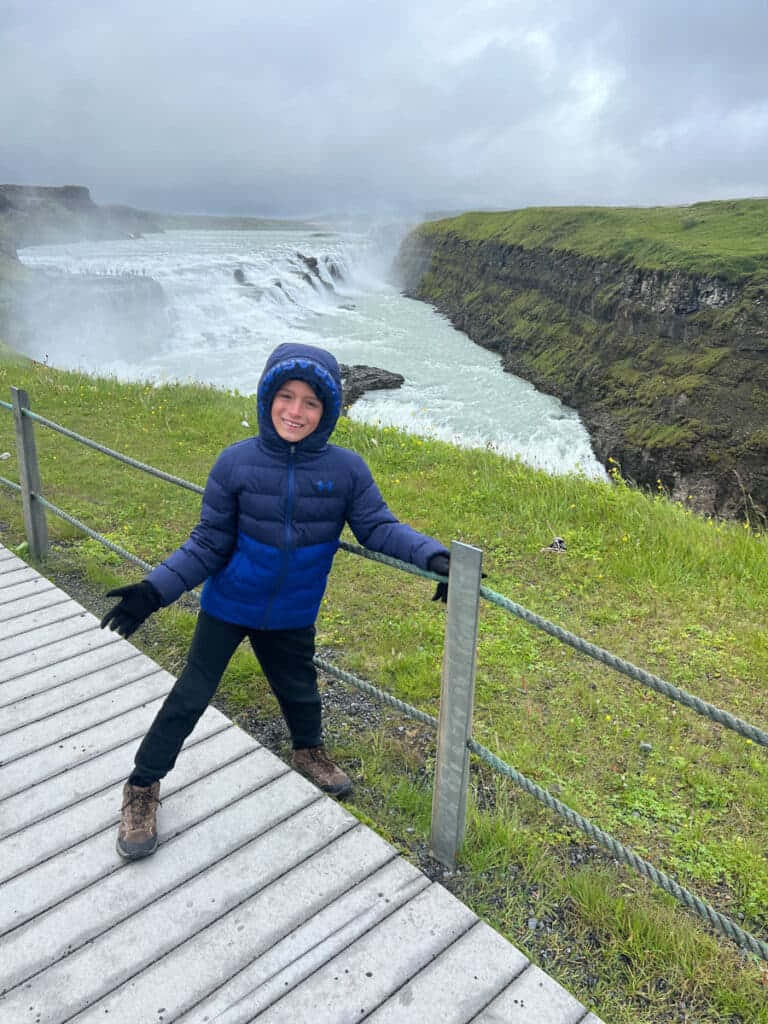 Kind wat Gullfoss-waterval in Suidwes-Ysland besoek Muurpapier