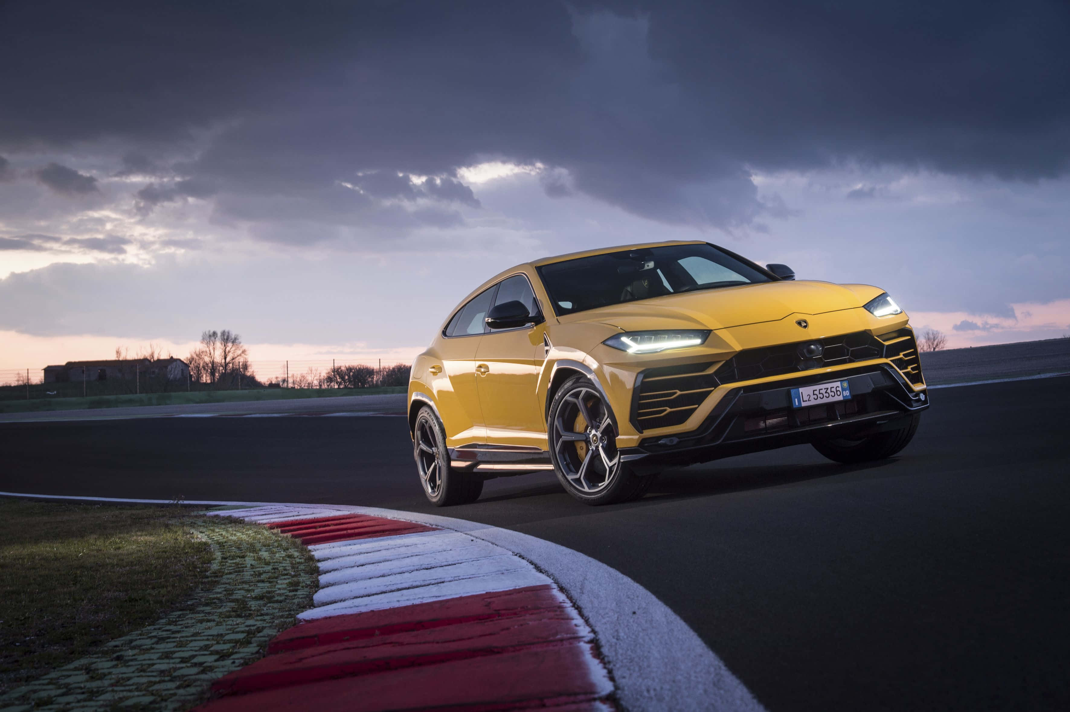 lamborghini urus - 'n geel sportnutsvoertuig wat op 'n baan ry Muurpapier
