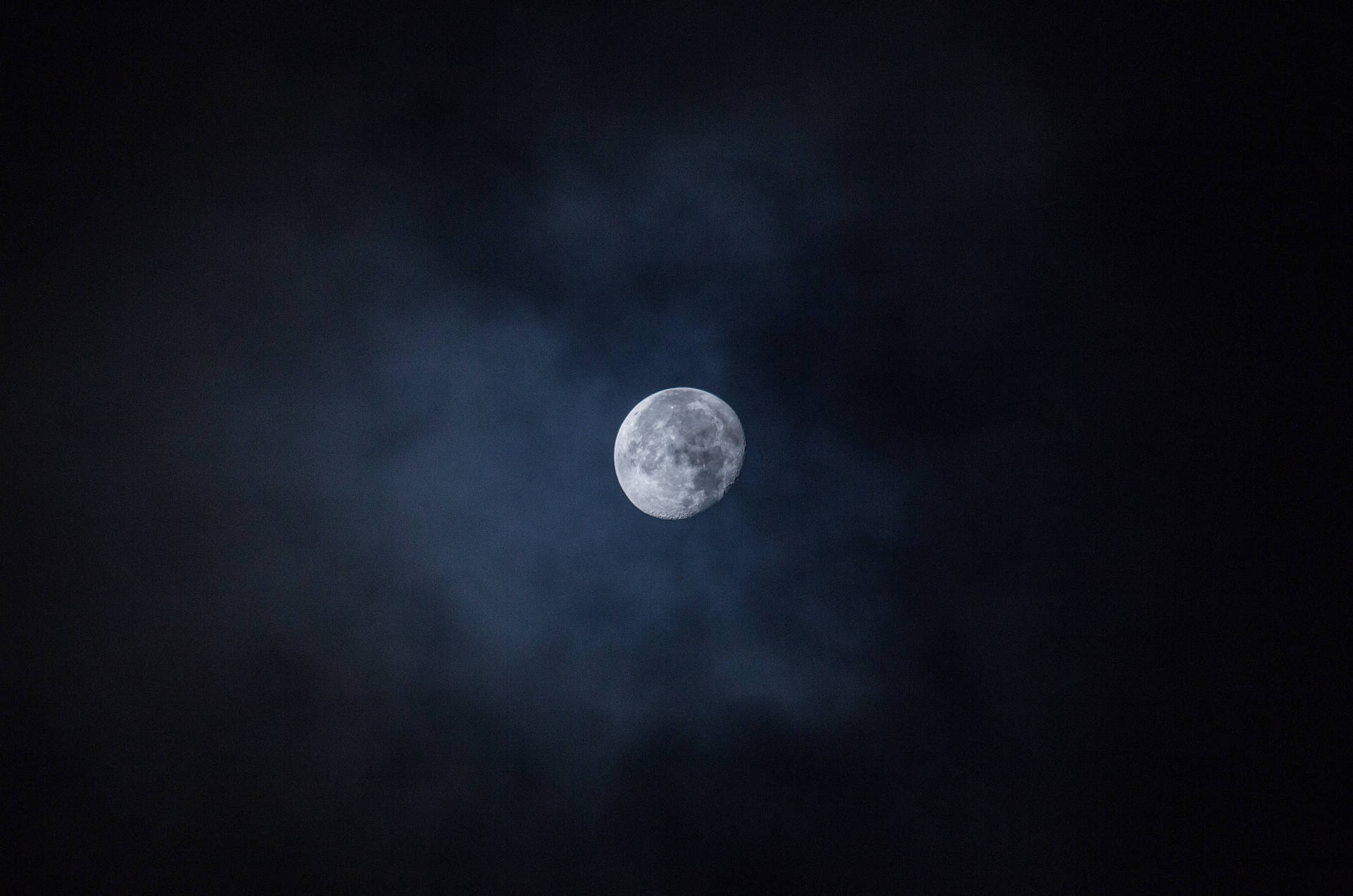 Helder maan wat in die donker lug skyn gedurende middernag. Volmaan bo wat die kraters wys.