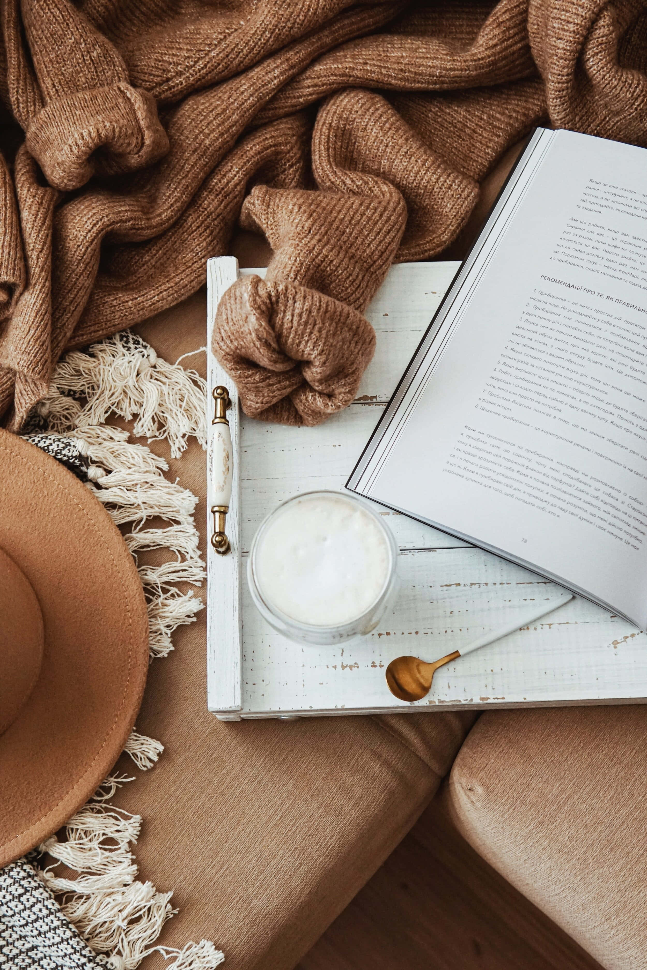 'n Boek, hoed en beker op 'n rusbank Muurpapier