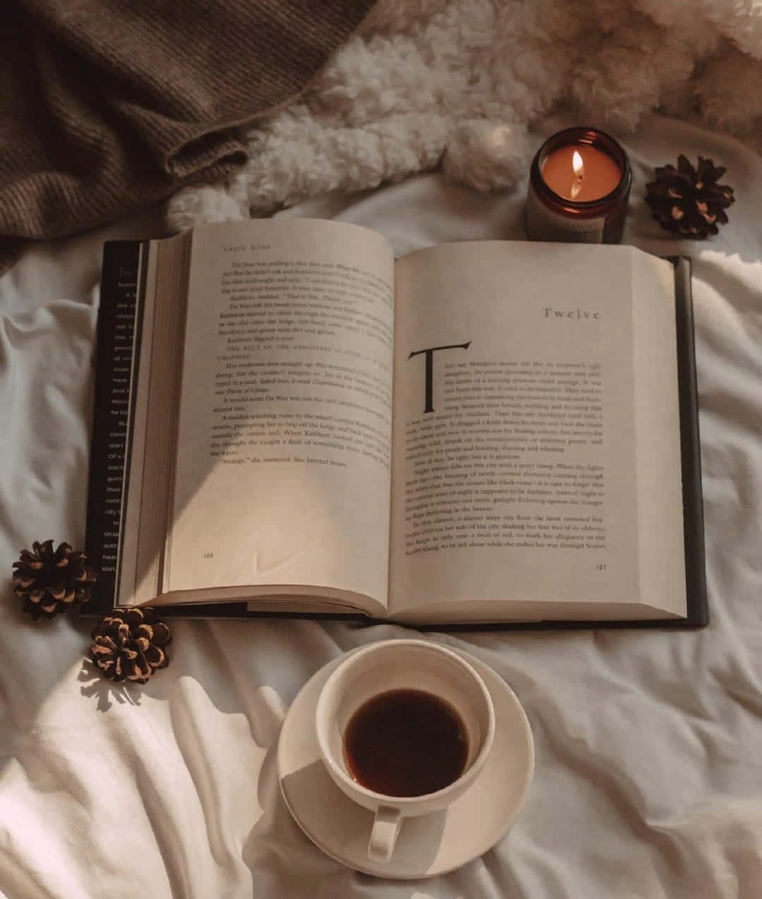 'n boek, kers en koppie koffie op 'n bed Muurpapier