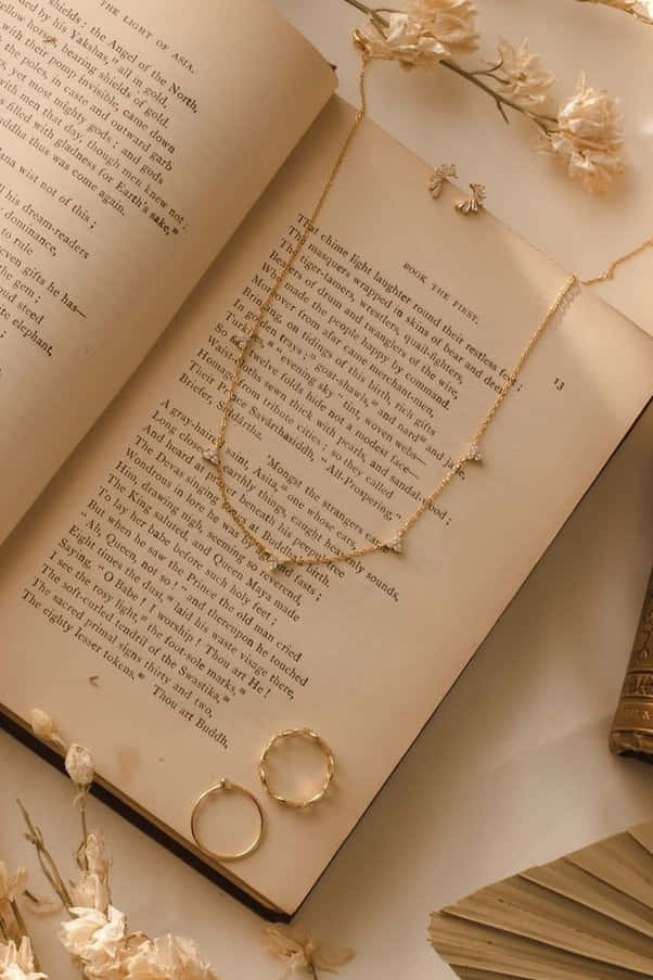 'n boek met 'n halssnoer en ring daarop Muurpapier