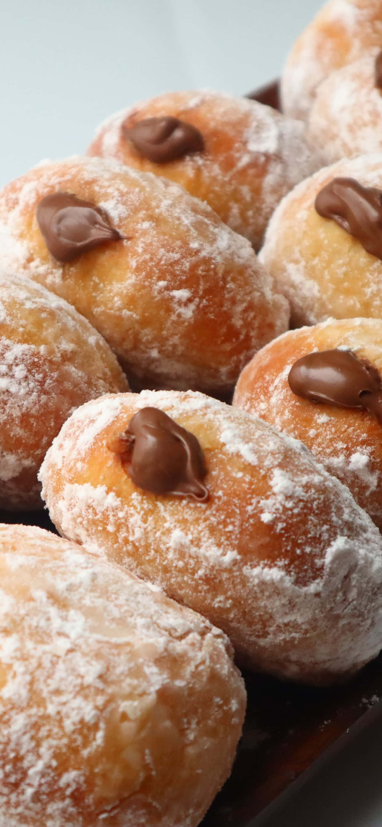 'n bord doughnuts met sjokolade en poeiersuiker Muurpapier