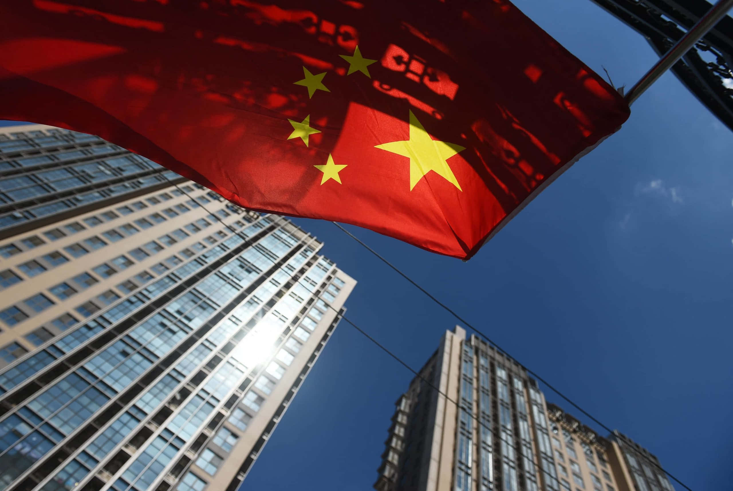 'n Chinese vlag wapper voor hoë geboue Muurpapier