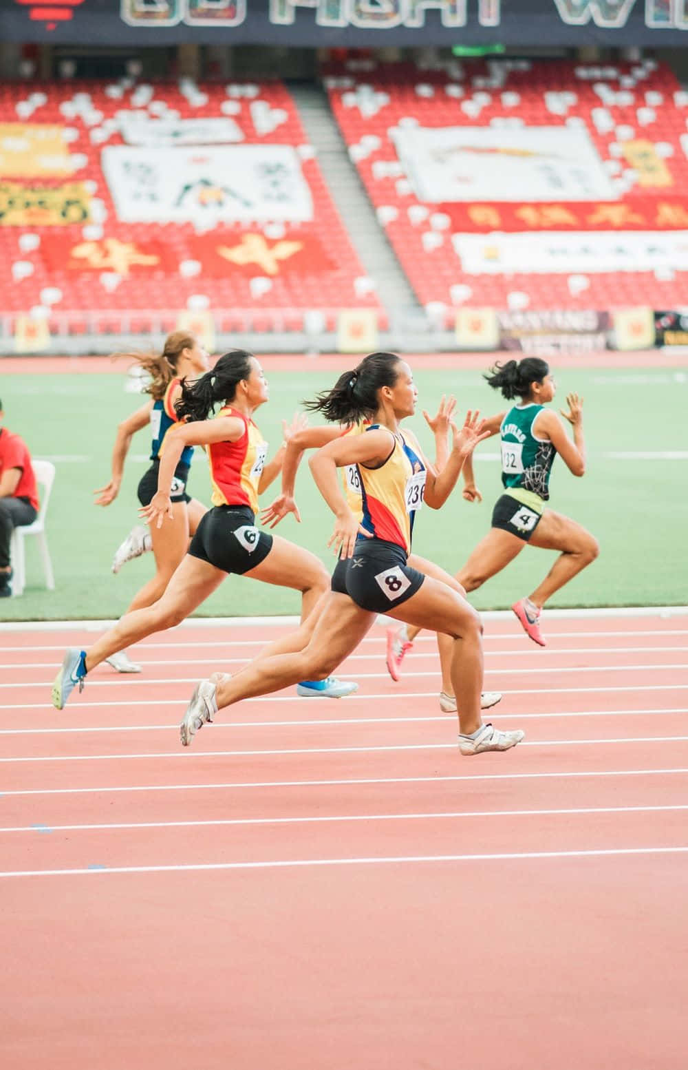 'n groep vroue wat op 'n baan in 'n stadion hardloop Muurpapier