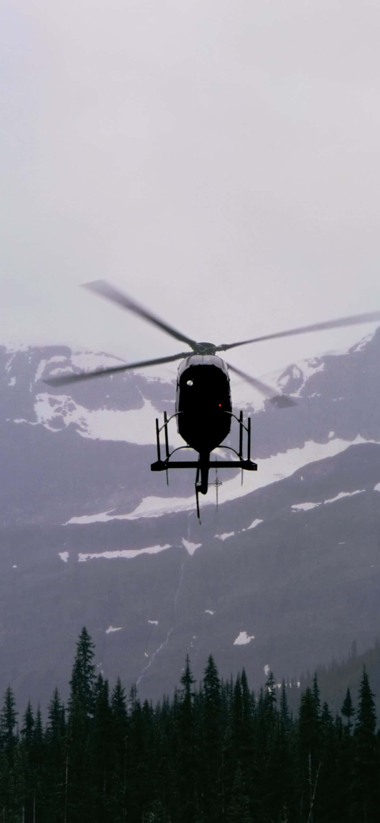 'n helikopter wat oor 'n bergreeks vlieg Muurpapier