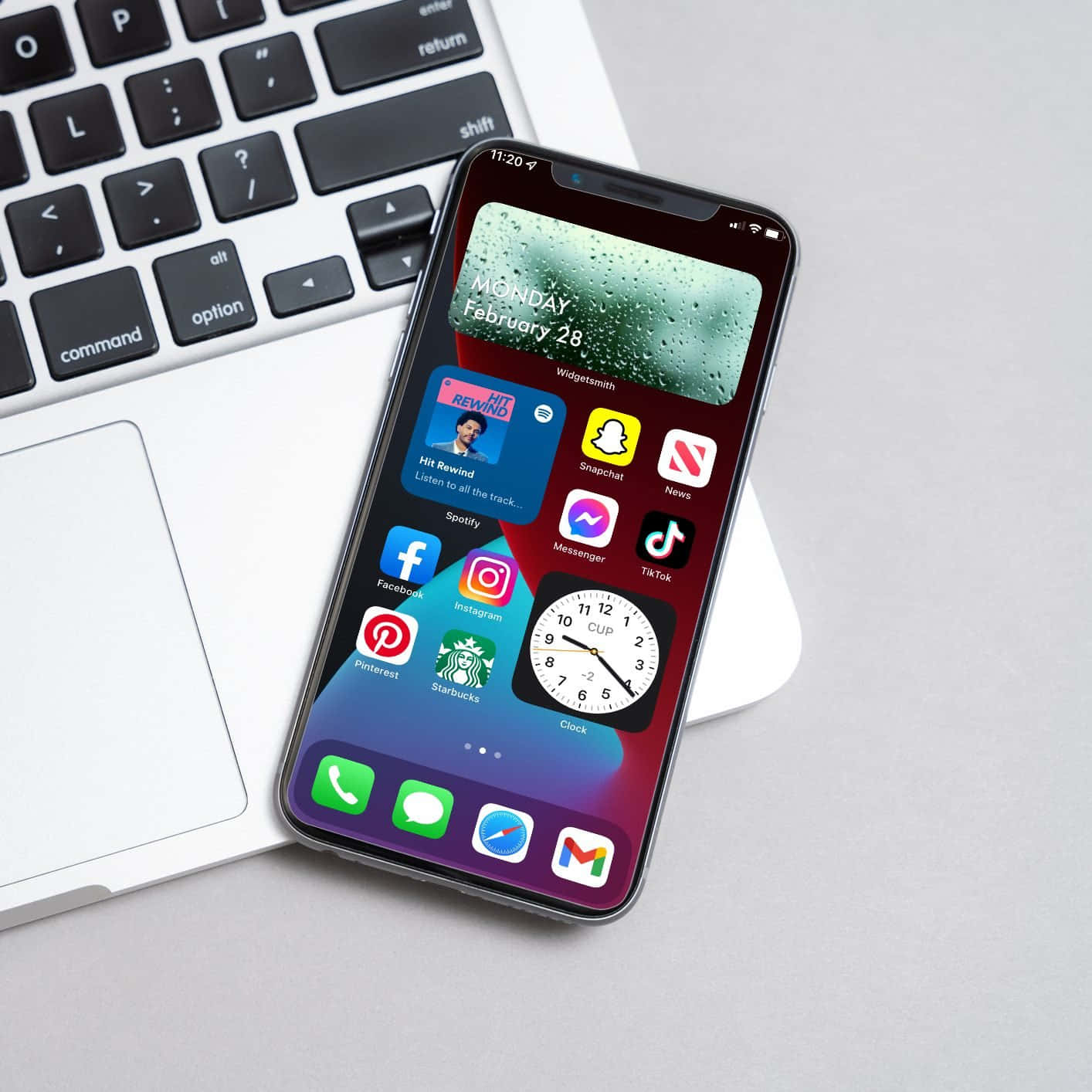 'n iPhone XR met programme daarop langs 'n skootrekenaar Muurpapier