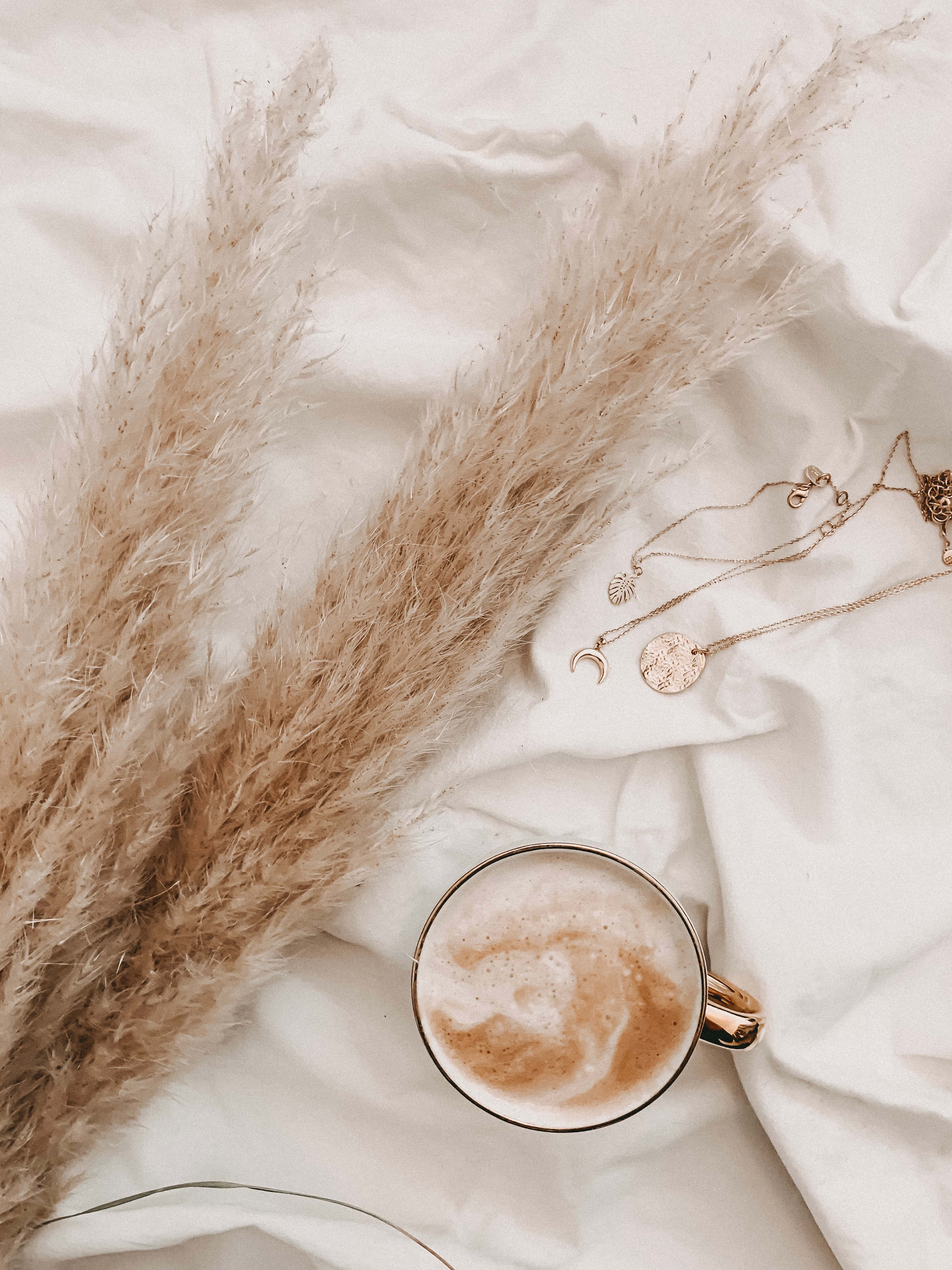 'n koppie koffie en 'n halssnoer op 'n bed Muurpapier