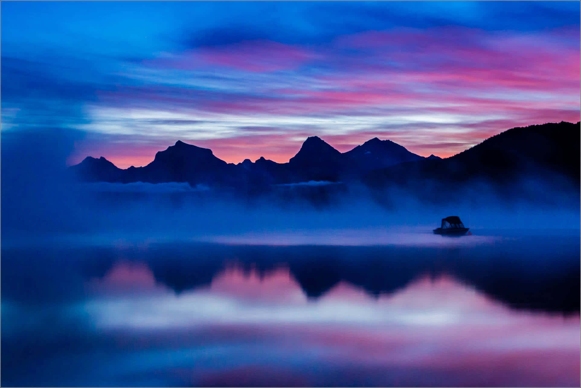 'n meer met berge en mis in die agtergrond Muurpapier