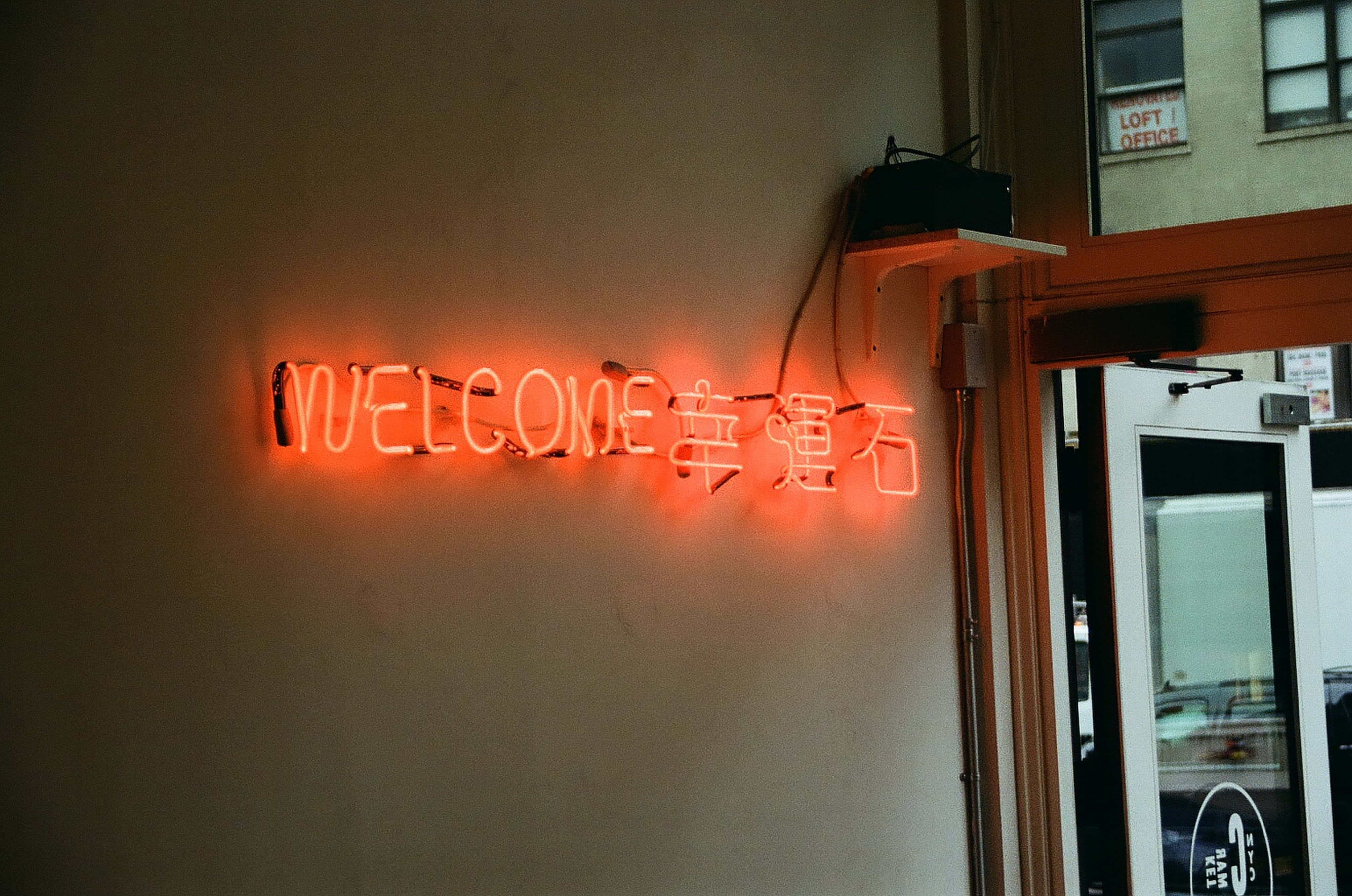 'n neon teken wat welkom sê teen 'n muur Muurpapier