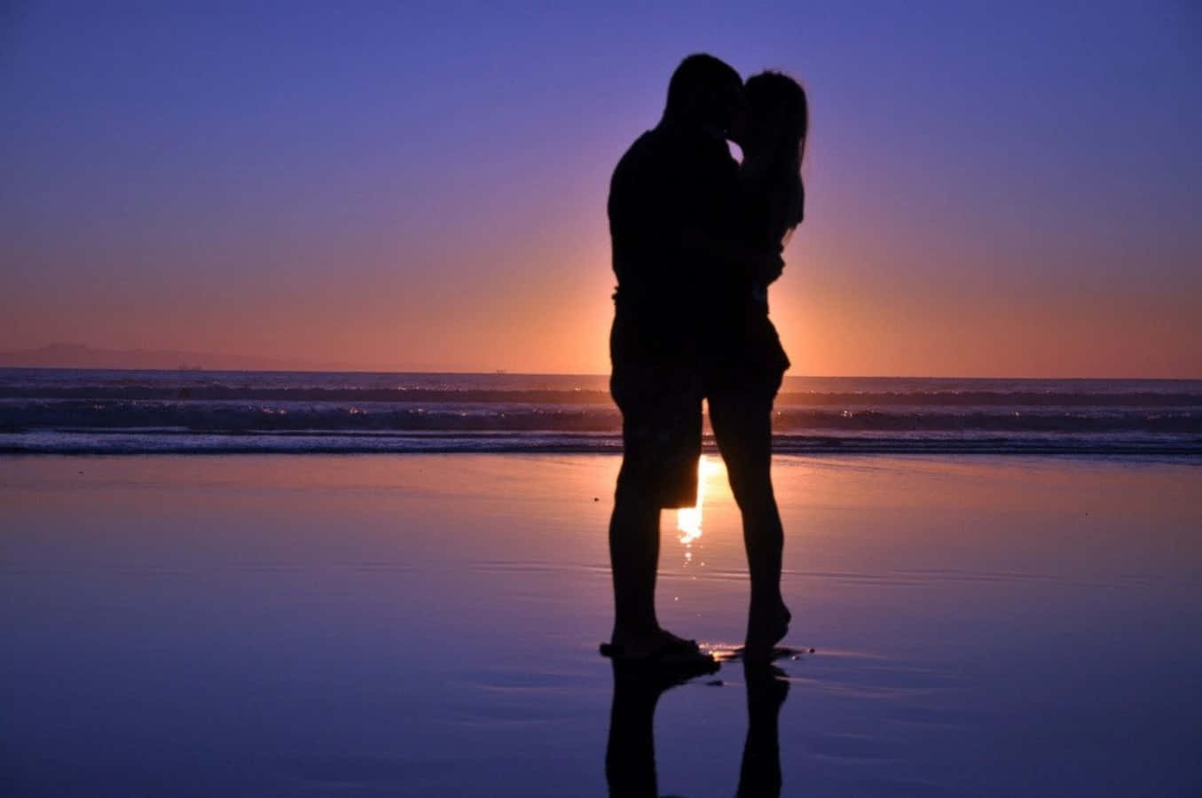 'n paartjie wat soen op die strand teen sonsondergang Muurpapier