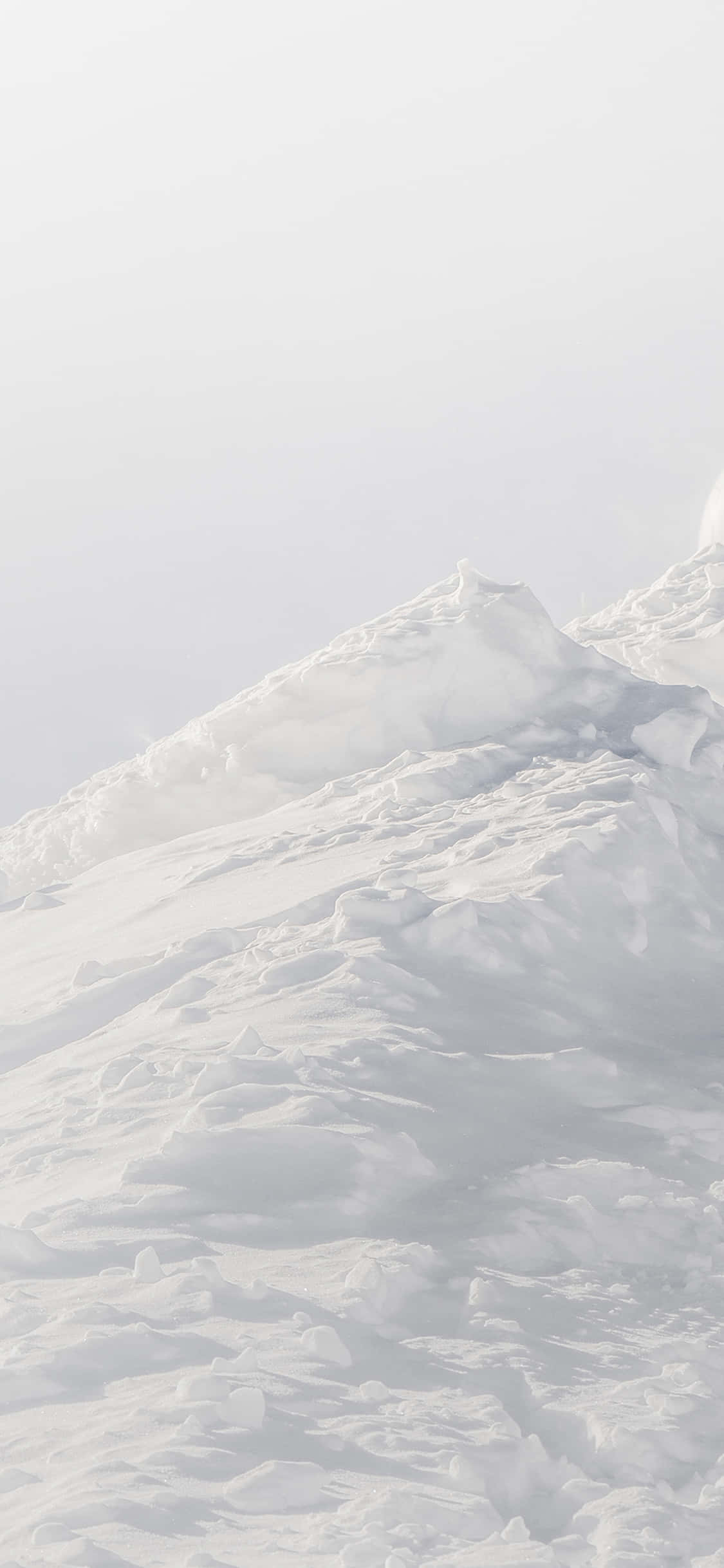 'n Persoon ski af 'n sneeubedekte helling Muurpapier