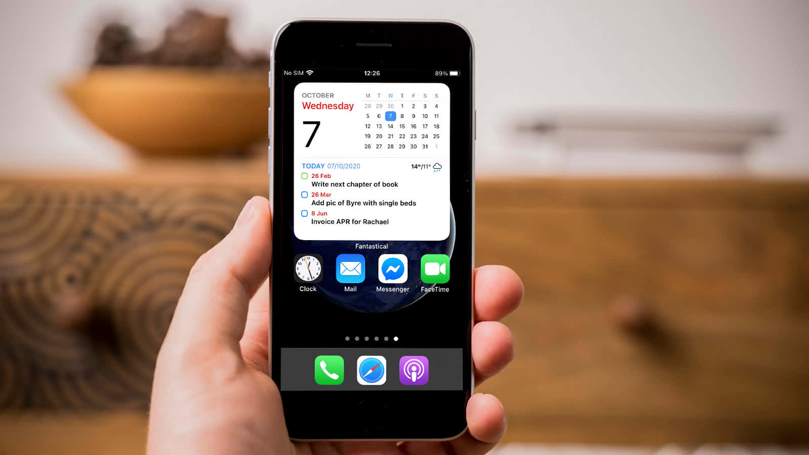 'n persoon wat 'n iPhone vashou met 'n kalender daarop Muurpapier