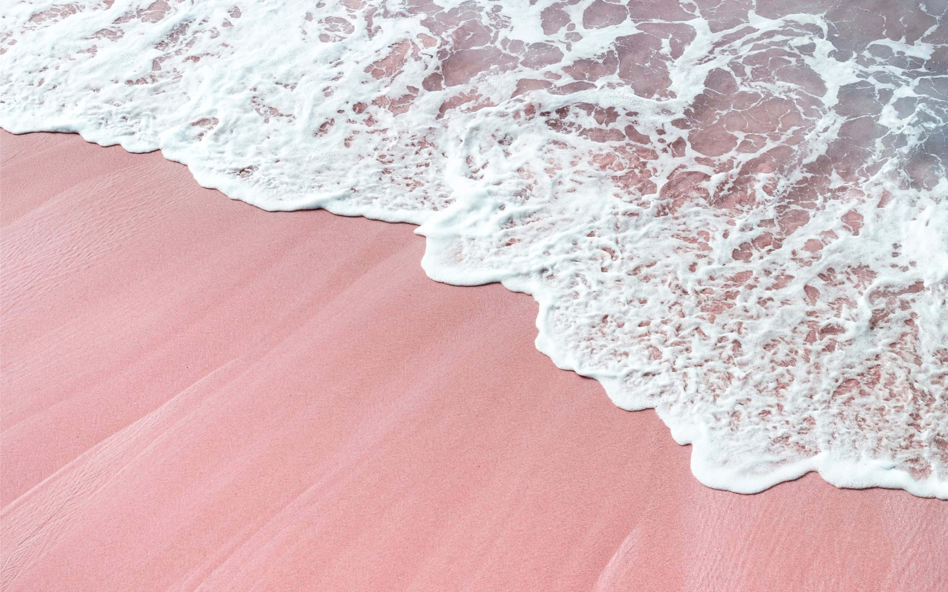 'n Pienk sandstrand met golwe en pienk sand Muurpapier
