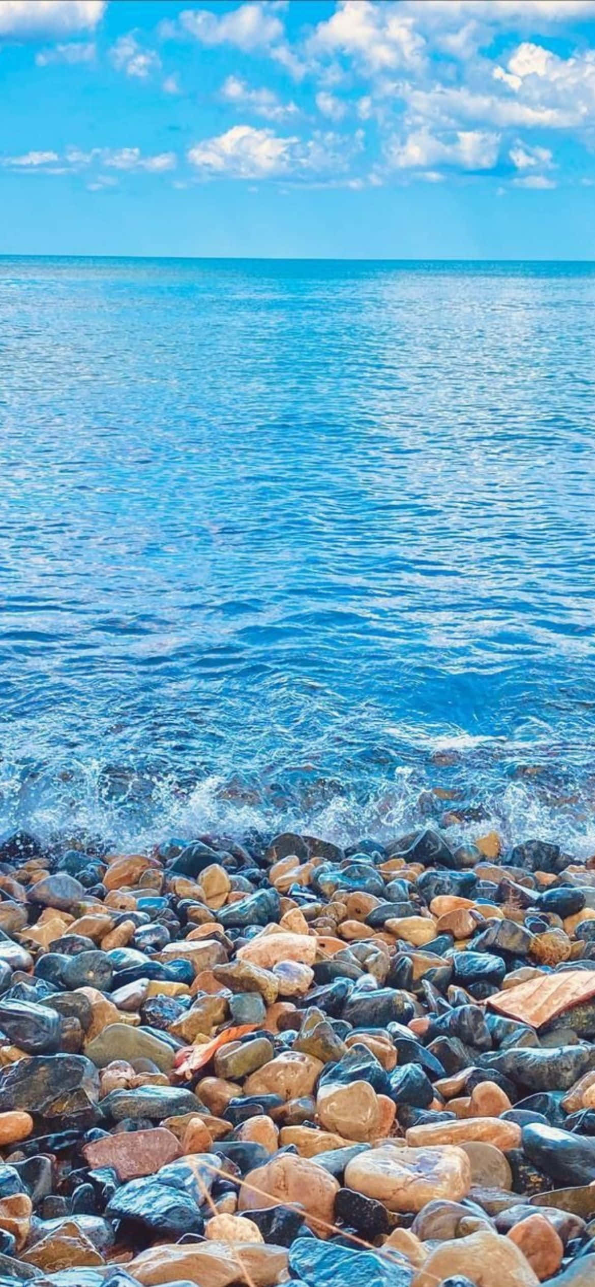 'n strand met rotse en water Muurpapier