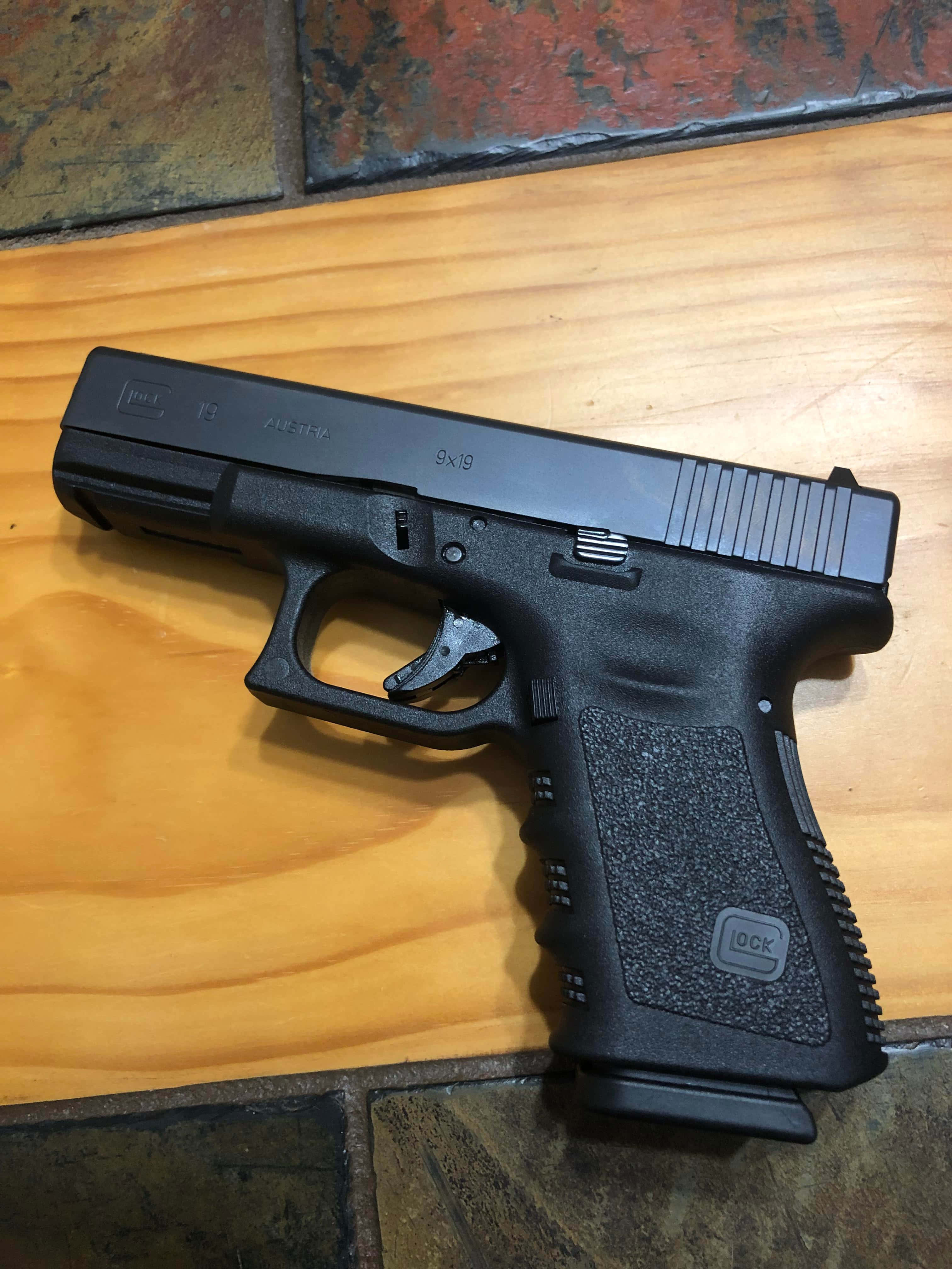 'n swart glock-pistool op 'n houtvloer Muurpapier