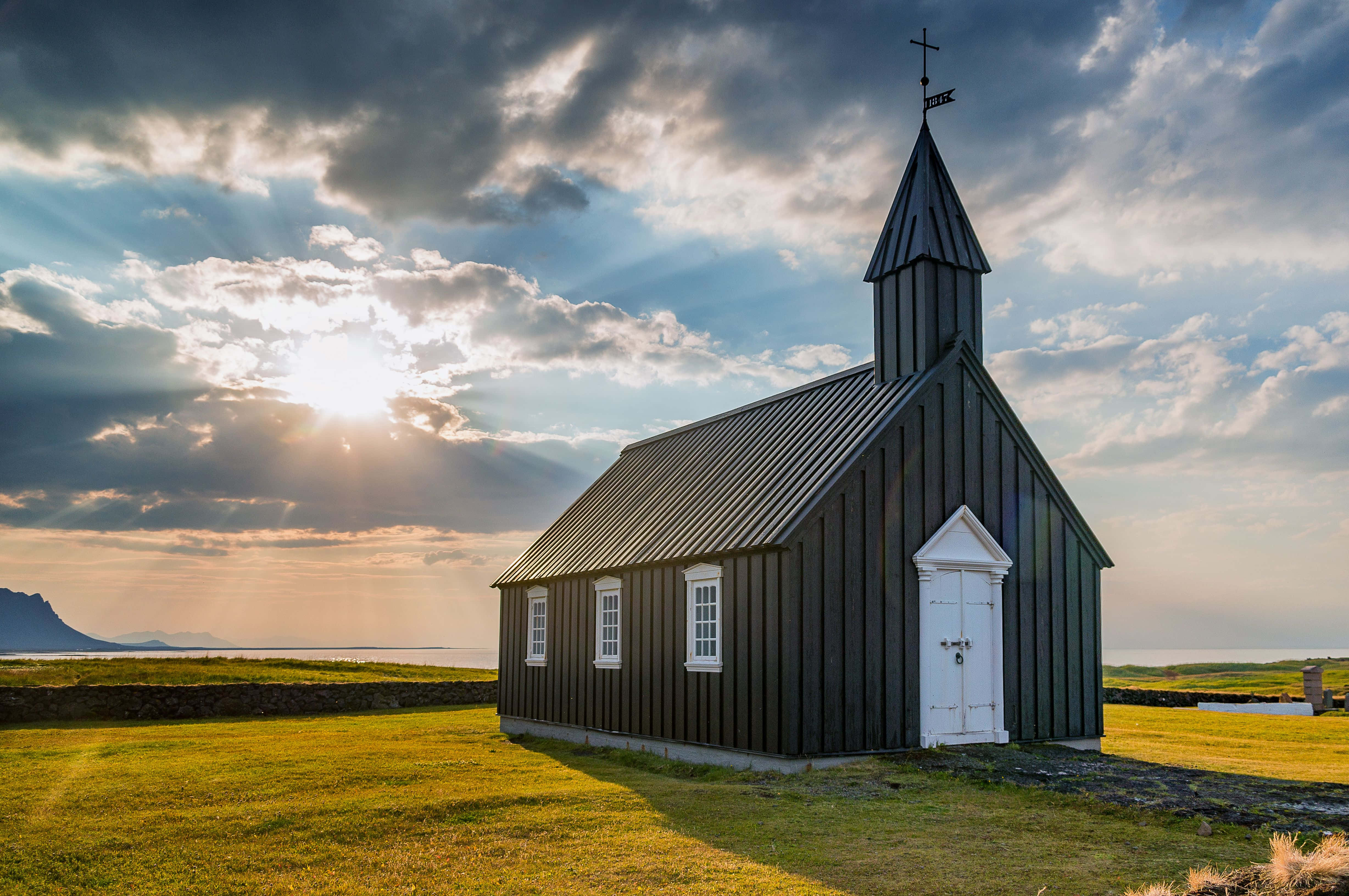 'n swart kerk staan op 'n grasveld Muurpapier