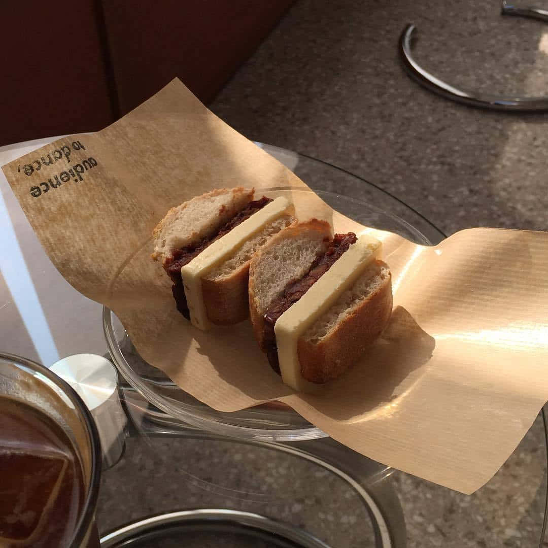 'n toebroodjie op 'n bord met 'n koppie koffie Muurpapier