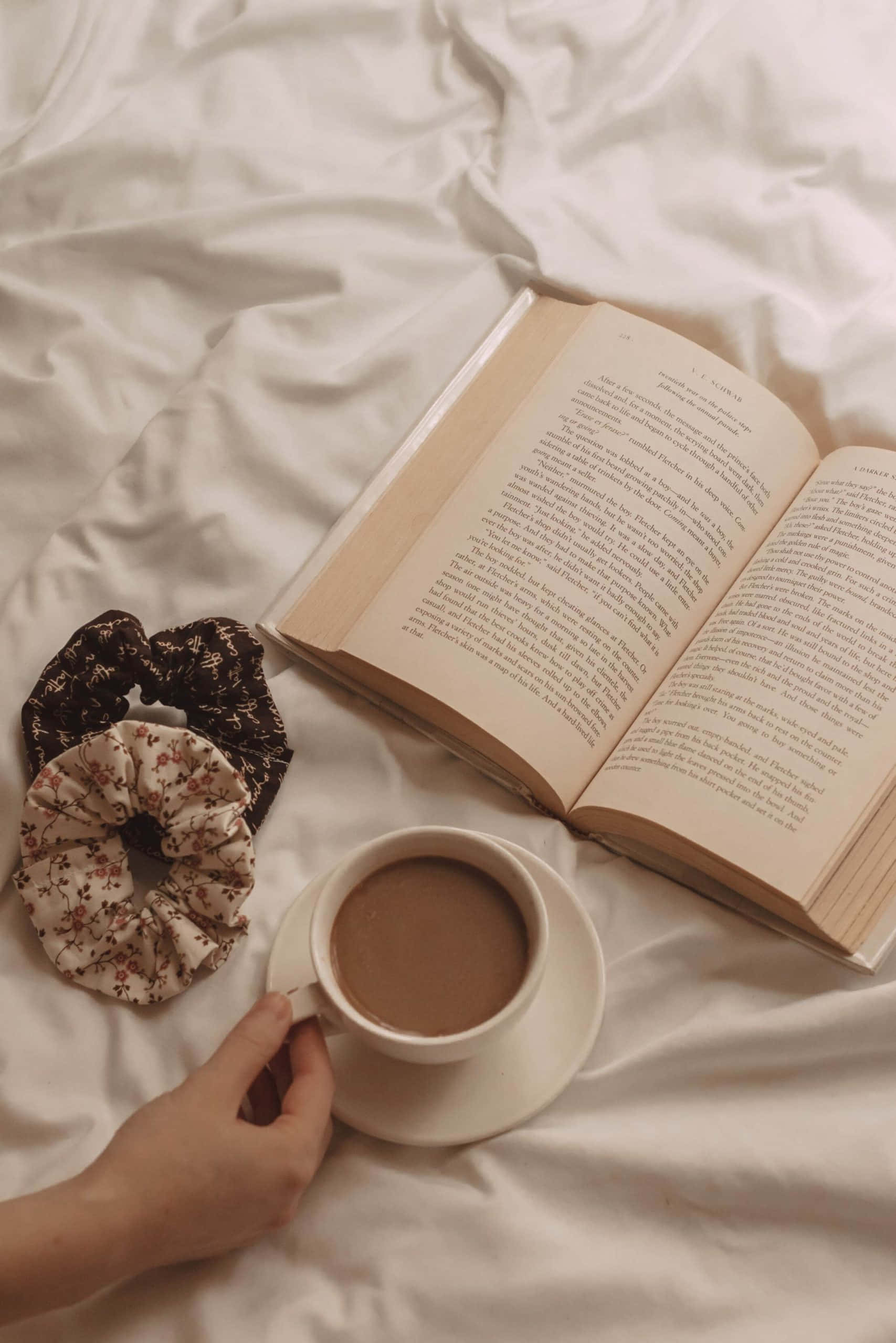 'n vrou se hand wat 'n boek en 'n koppie koffie vashou Muurpapier