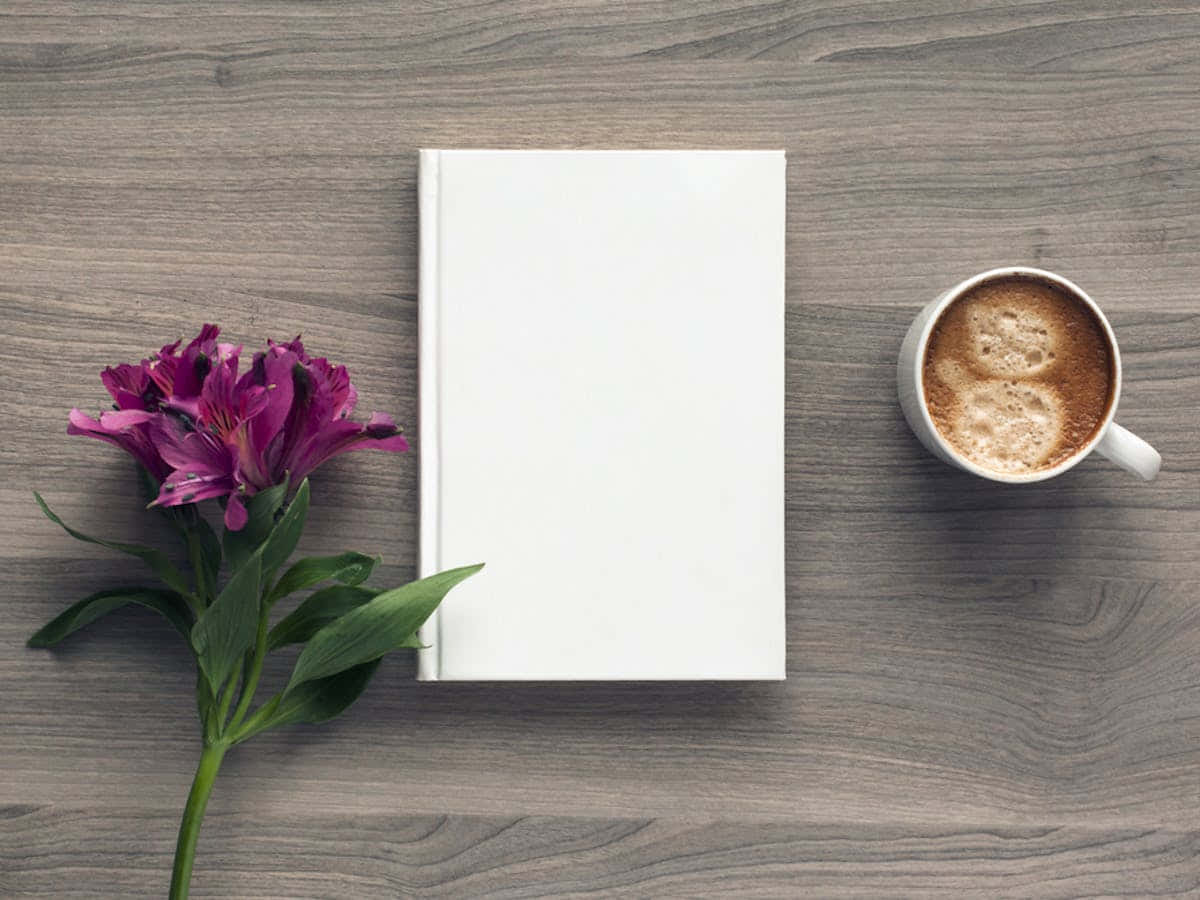 'n wit boek en 'n koppie koffie op 'n houttafel Muurpapier