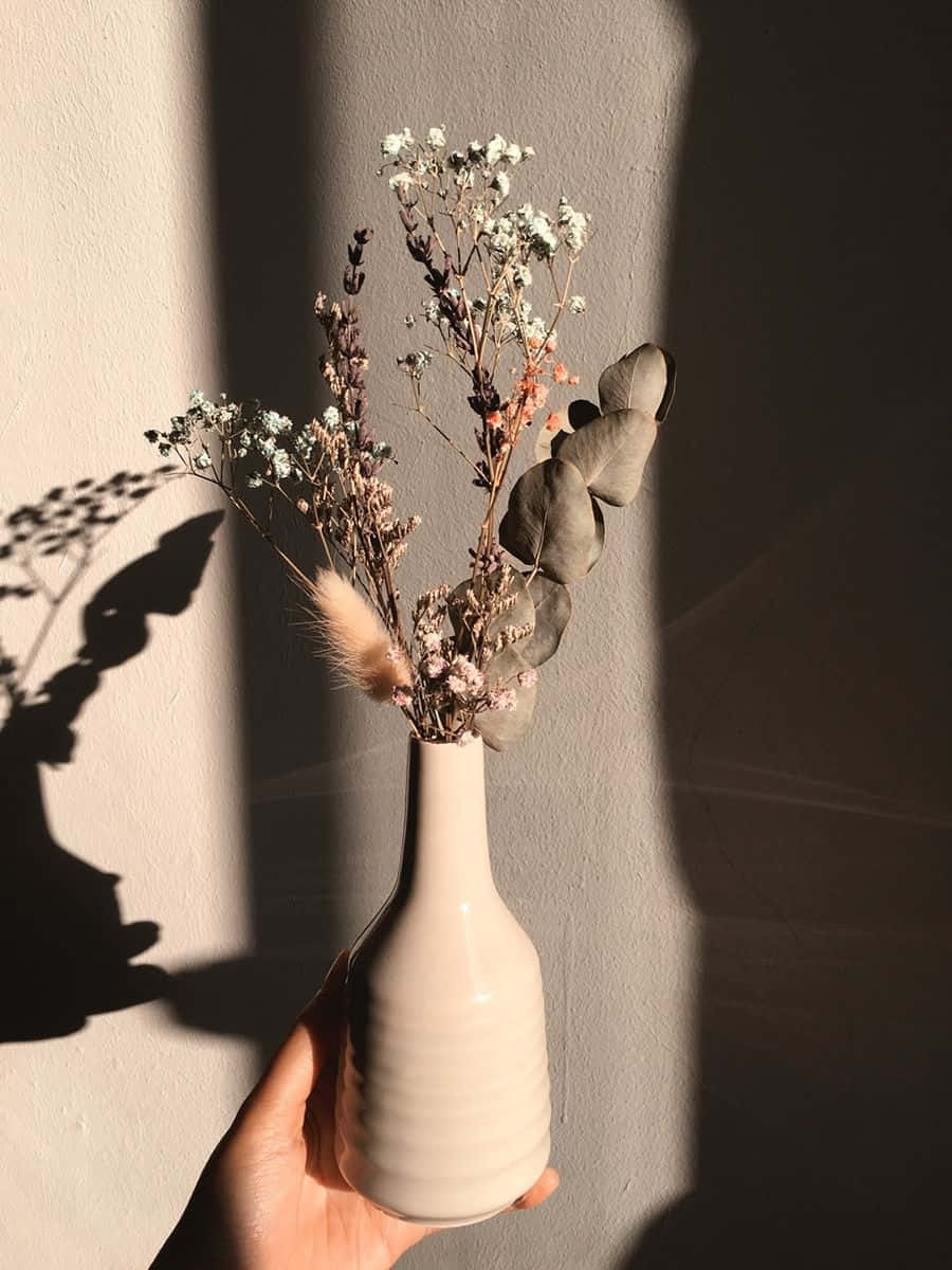 'n Wit vaas met 'n paar droë blomme daarin Muurpapier