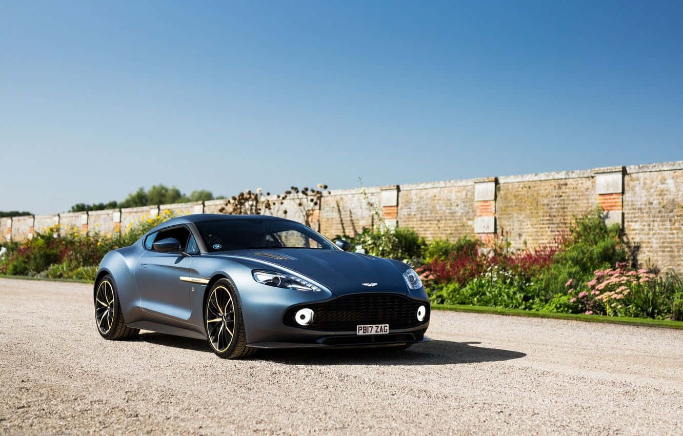 Pragtige Aston Martin Vanquish in beweging op 'n natuurskone pad Muurpapier