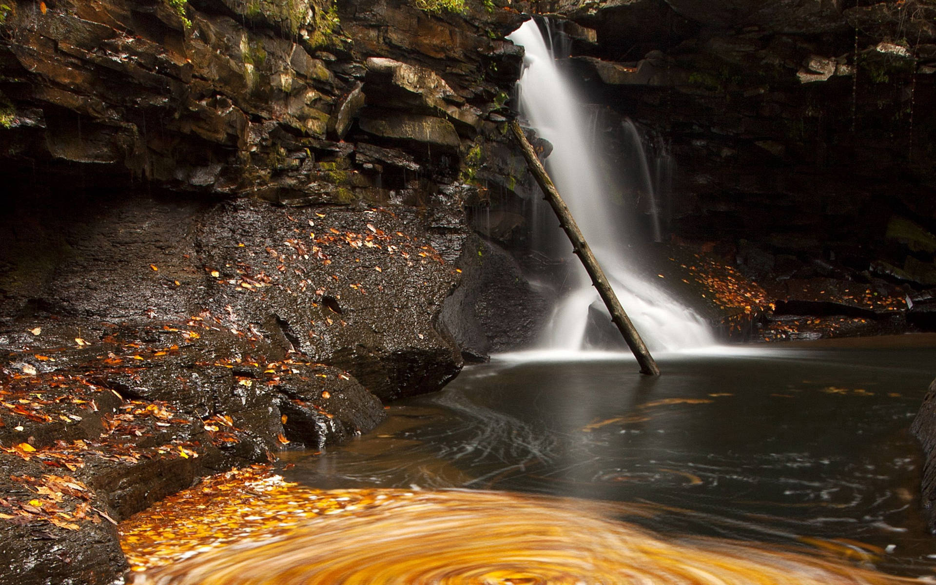 Waterval met ’n donker rotsrivier-agtergrond.