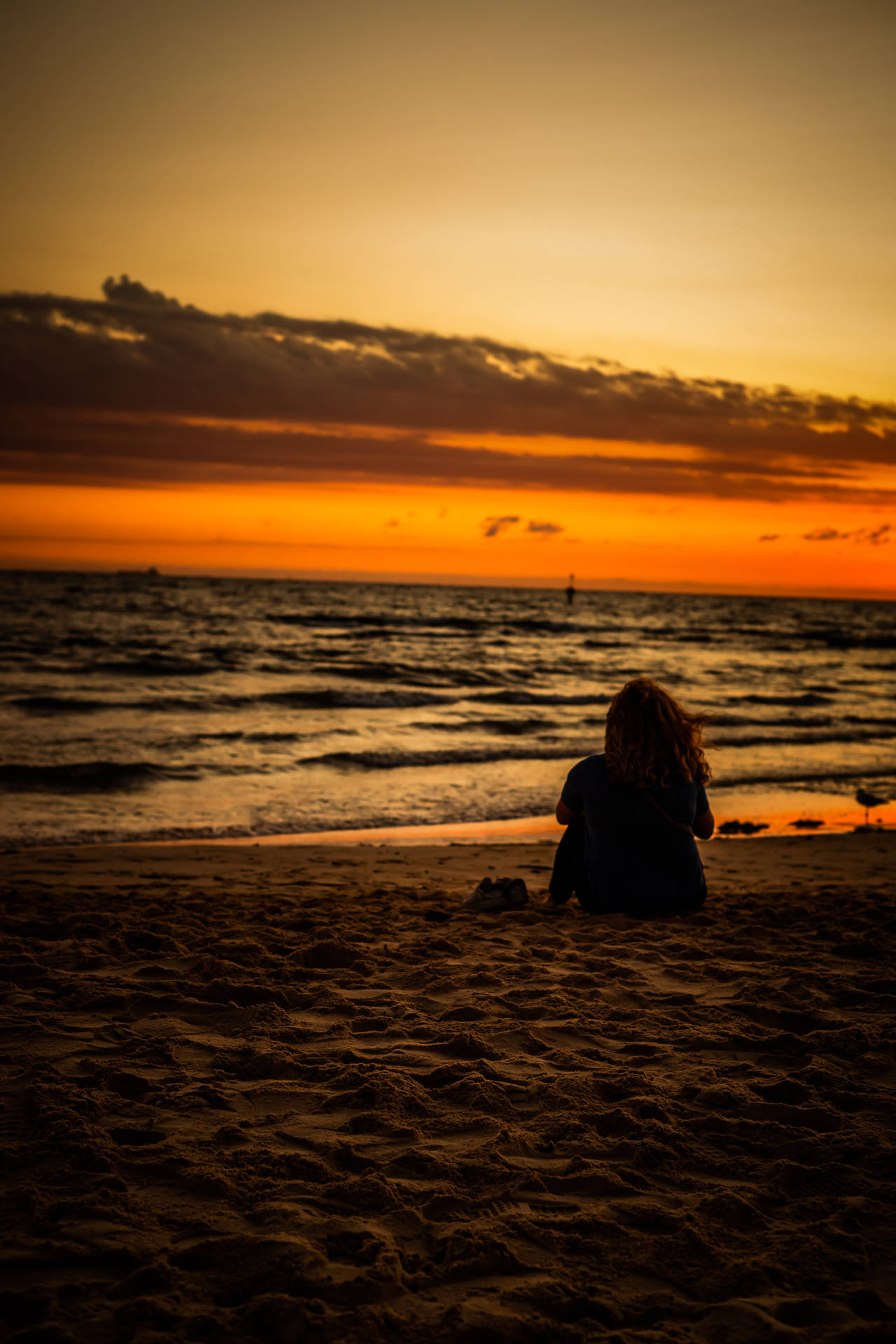 Vrou wat op die strand sit-agtergrond.