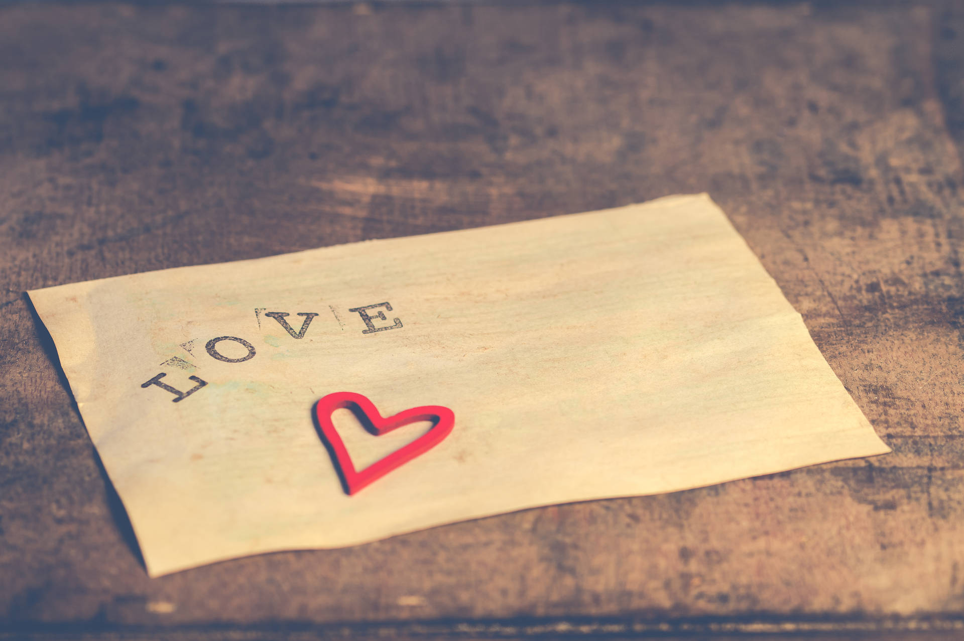 Brief met die woord "Liefde" getik daarop en oulike klein rooi hartplakker vir liefdesverklaring op Valentynsdag.