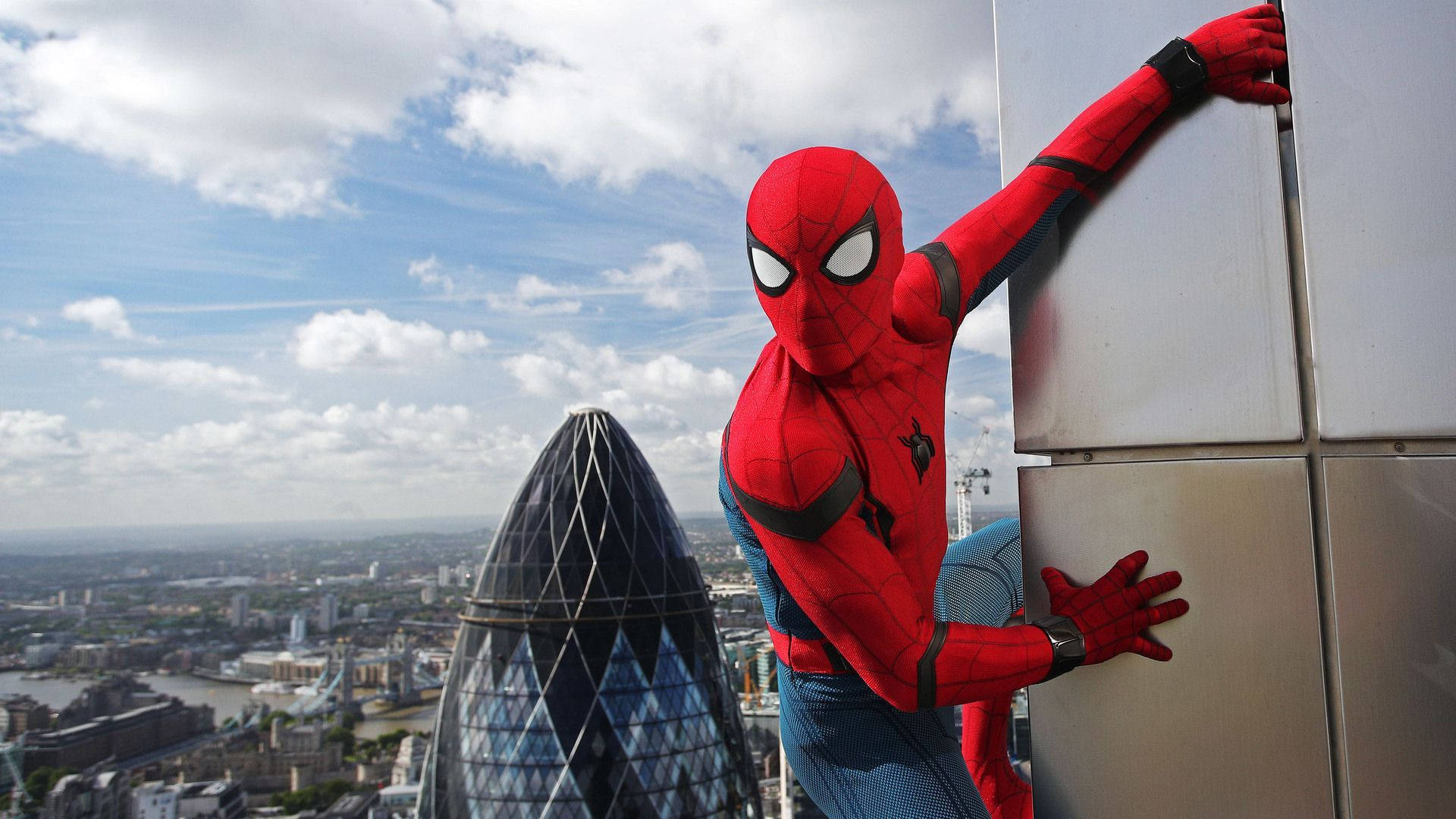 Spiderman wat aan die rand van 'n gebou vashou en staan.