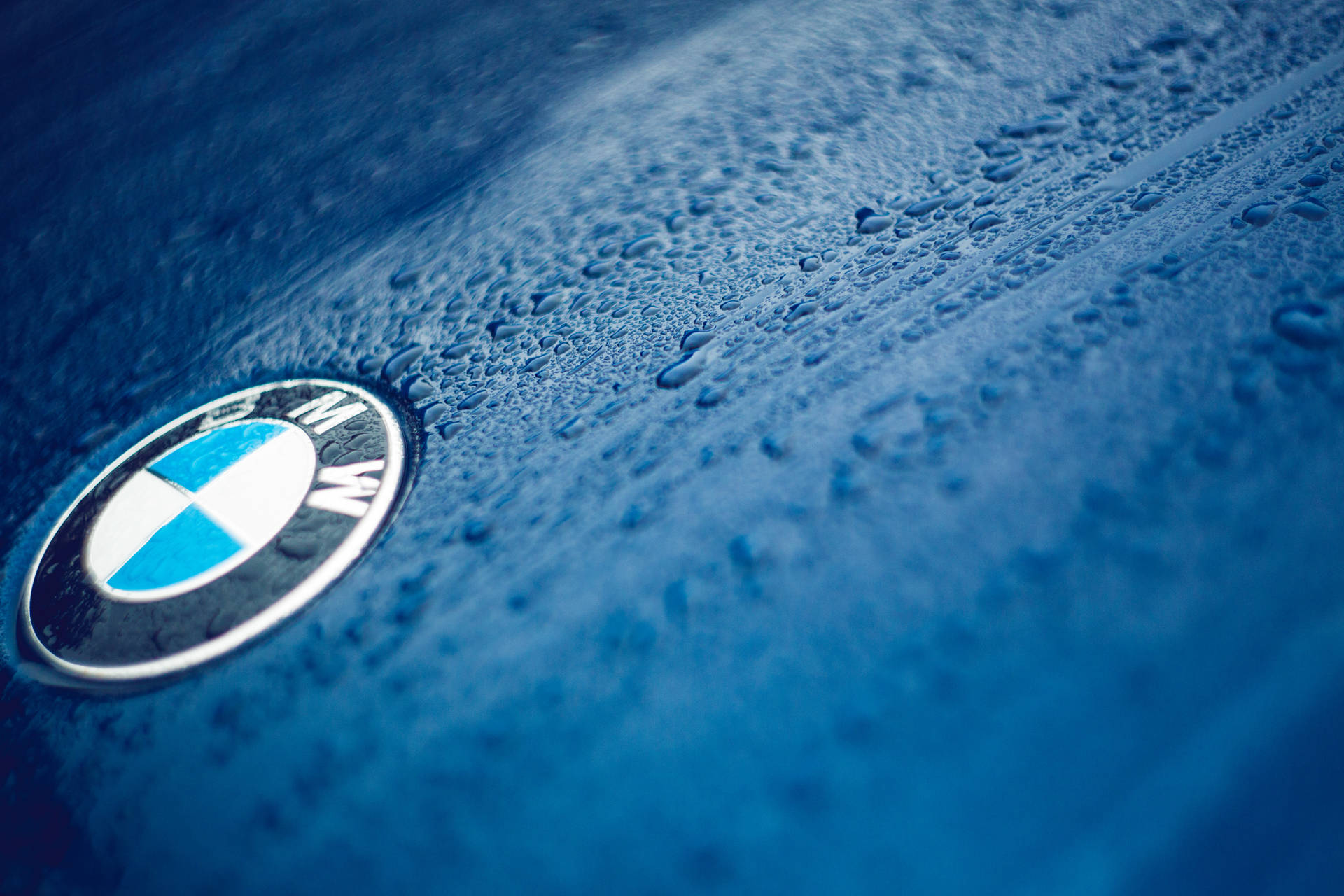 Nabyfoto agtergrond van BMW-logo op blou motor met druppels