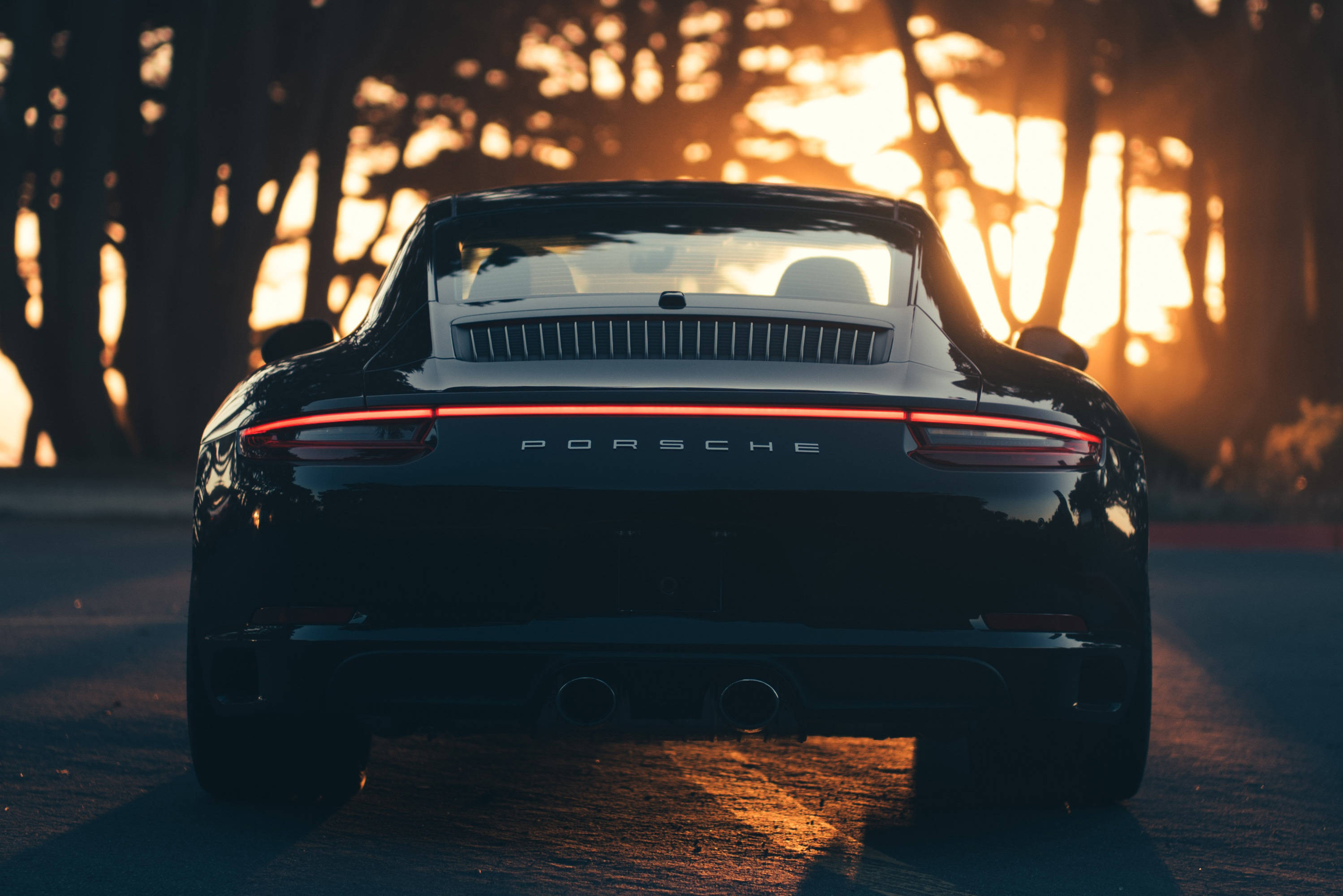 Swart Porsche 911 wat die sonsondergang aanskou Muurpapier