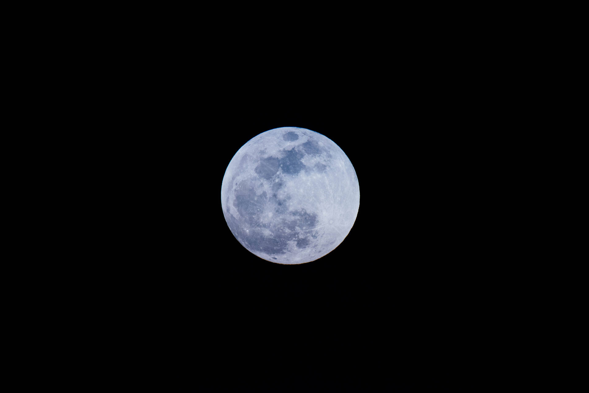 Volmaan wat helder skyn in die middernagtelike aandhemel. Maankraters wat op die oppervlak sigbaar is.