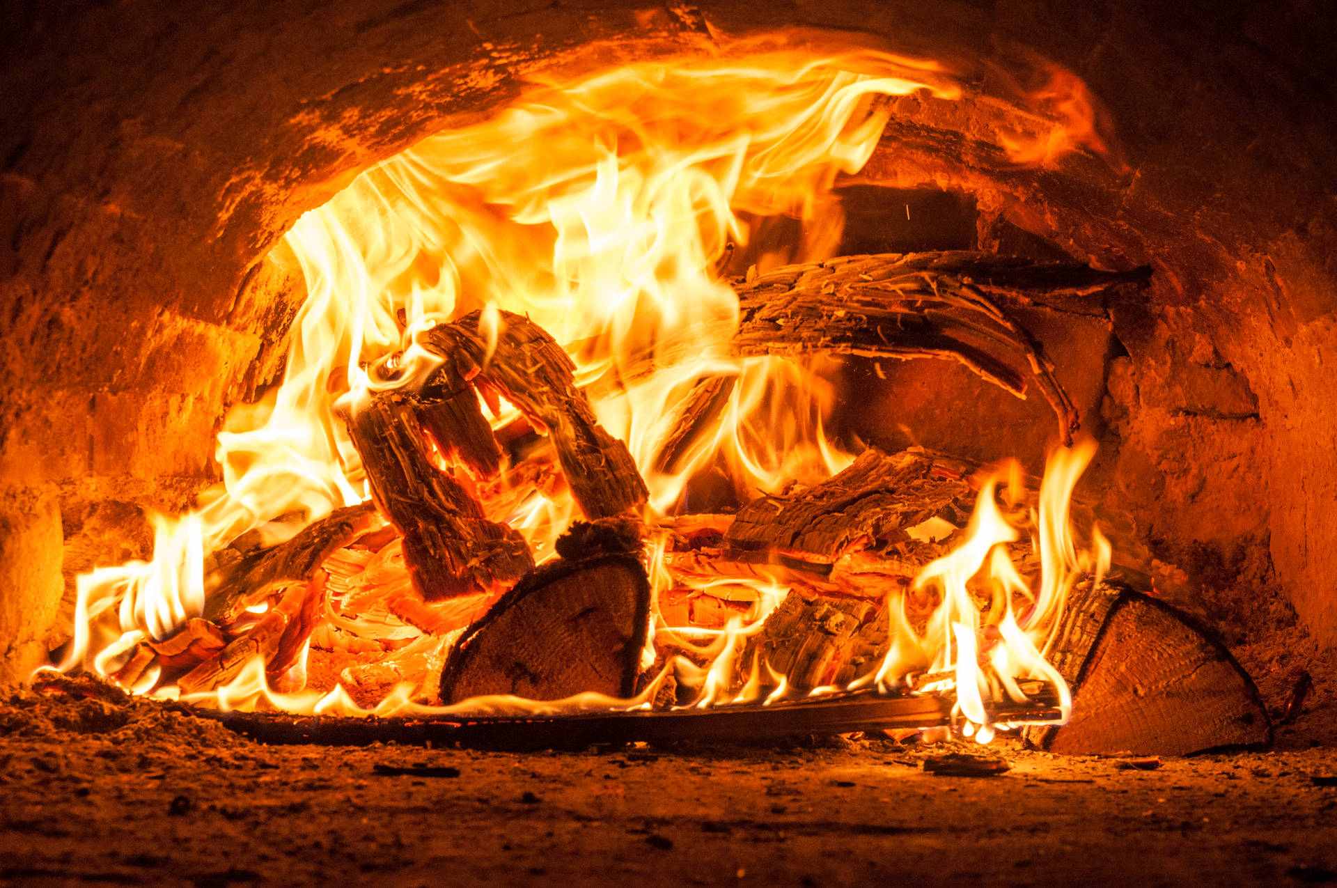 Kaggel met brandende hout en helder gloeiende vlamme binne-in 'n ou klein vuurmaakhoutgrot.