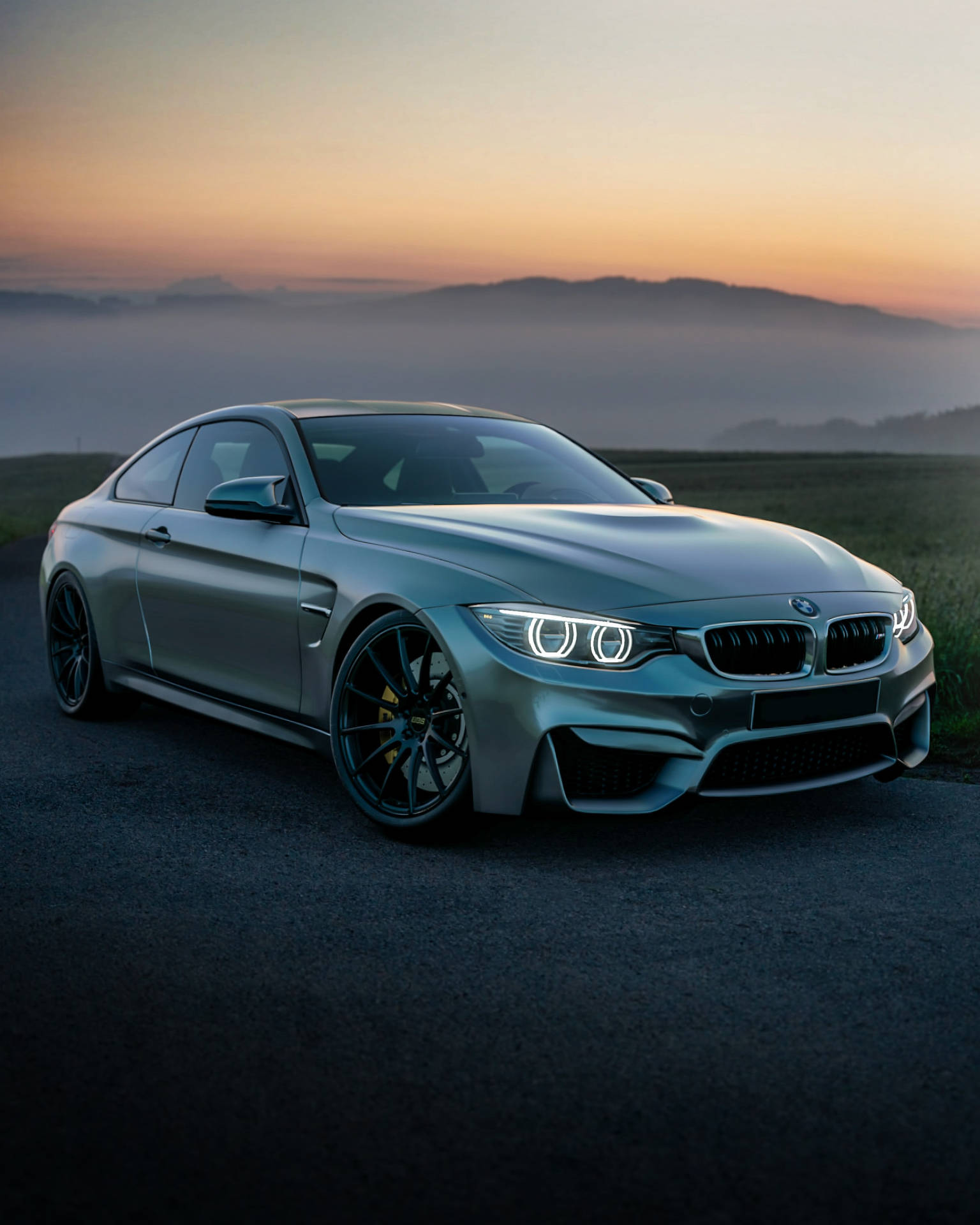 Grys BMW F83 M4-motor op berg met sonsopkoms agtergrond